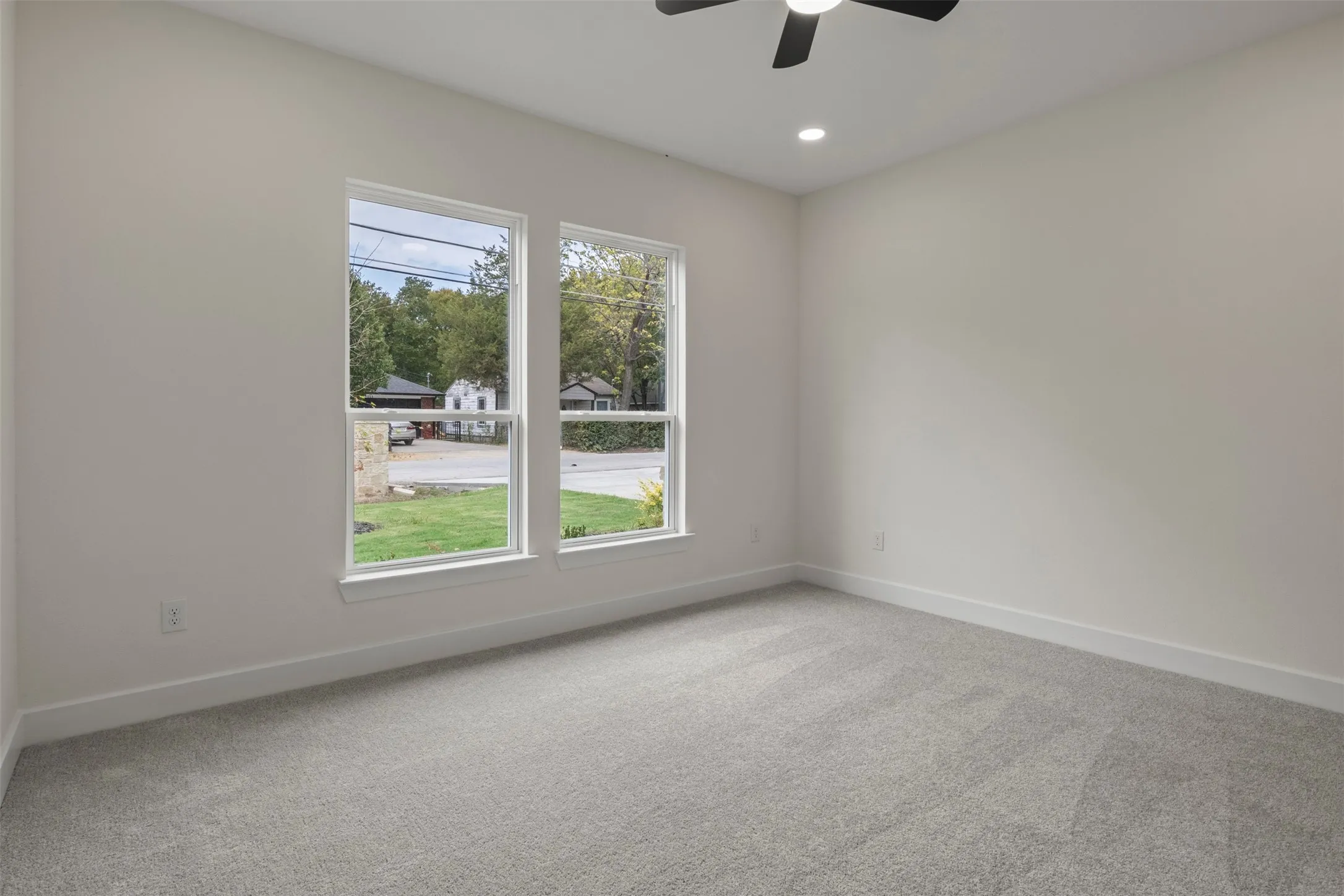 Neutral wall paint with two large windows, recessed lighting, and a ceiling fan