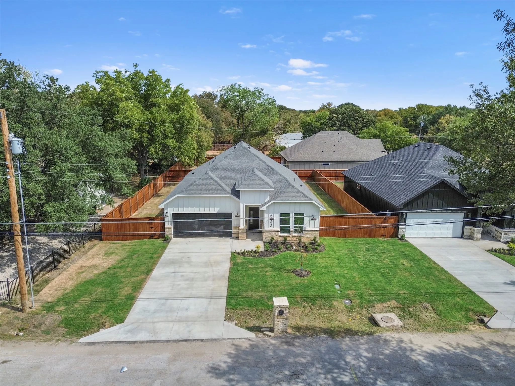 Contemporary single-story residence with a dark shingle roof, white vertical siding, and a stone facade accent
