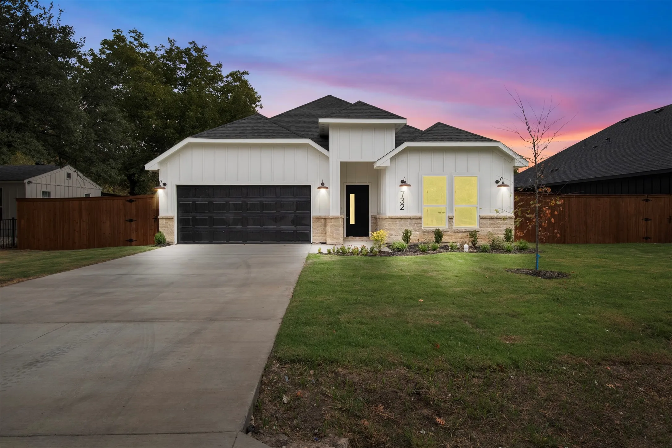 Contemporary exterior featuring vertical white siding, stone accents, and a dark asphalt shingle roof