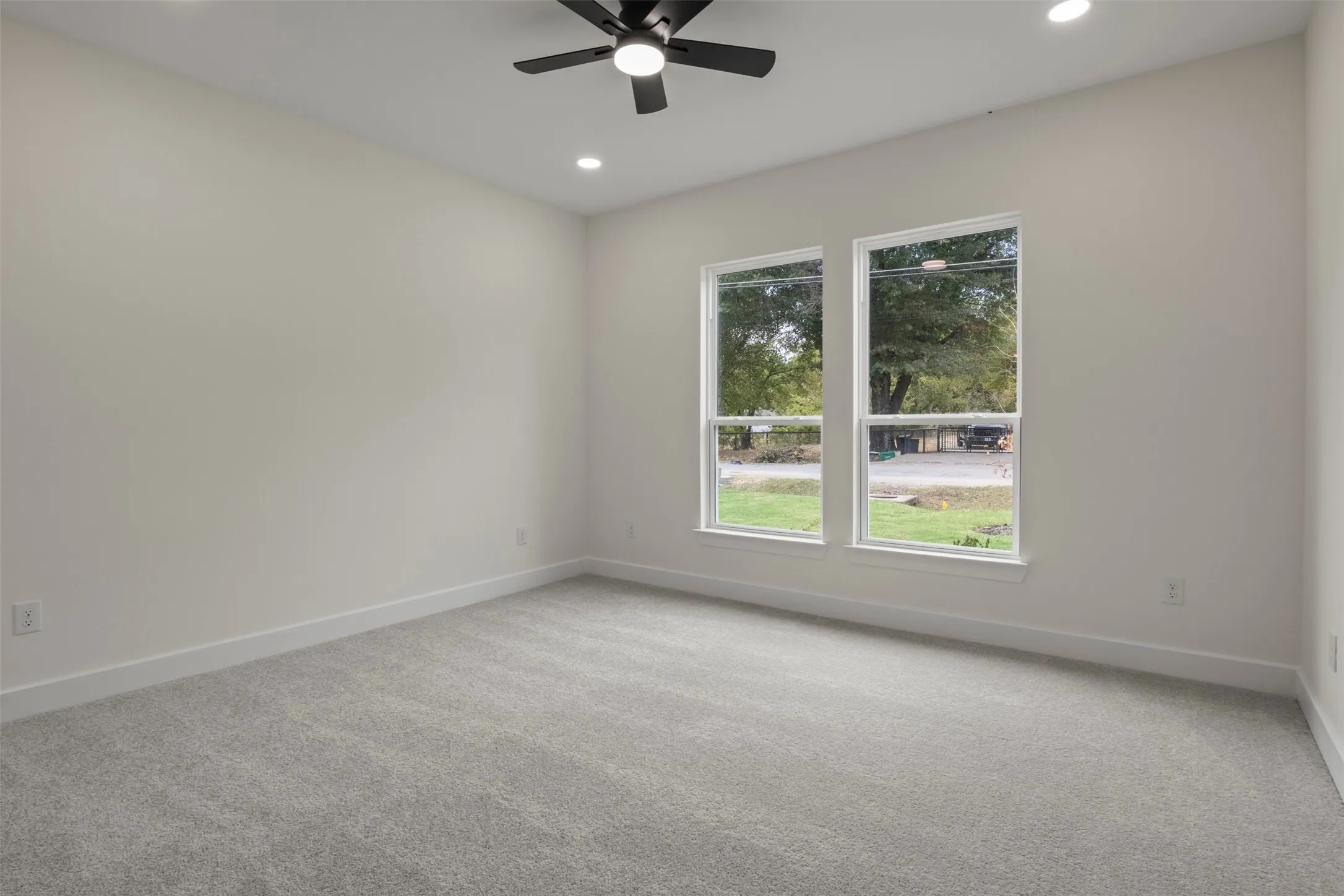 Spacious room featuring two large windows, recessed lighting, a ceiling fan, and light gray carpeting