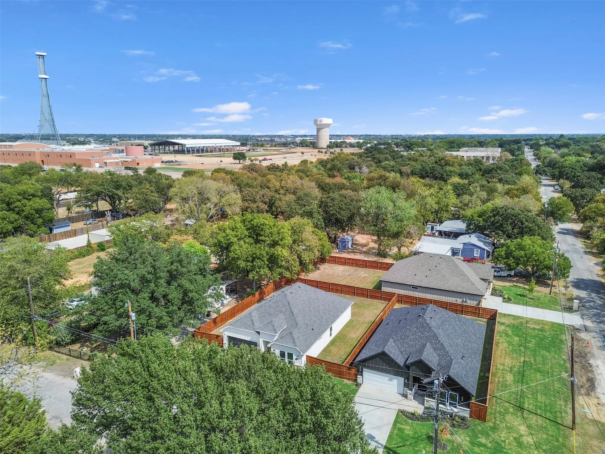 Aerial perspective showcasing a residential lot with a new construction property featuring a dark shingle roof and a light-colored exterior