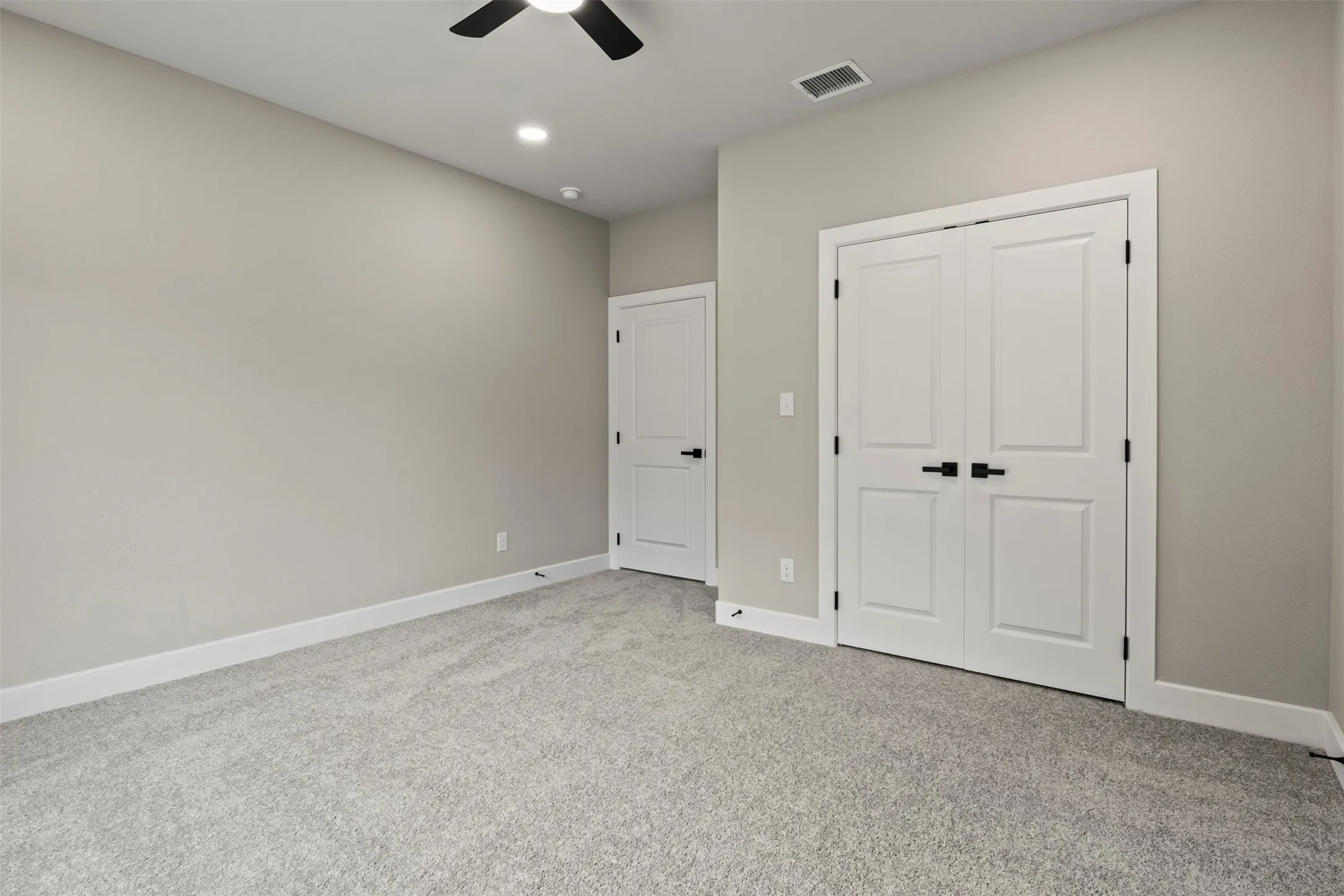 Plush carpet flooring, recessed ceiling lighting, ceiling fan, and white paneled doors with matte black hardware