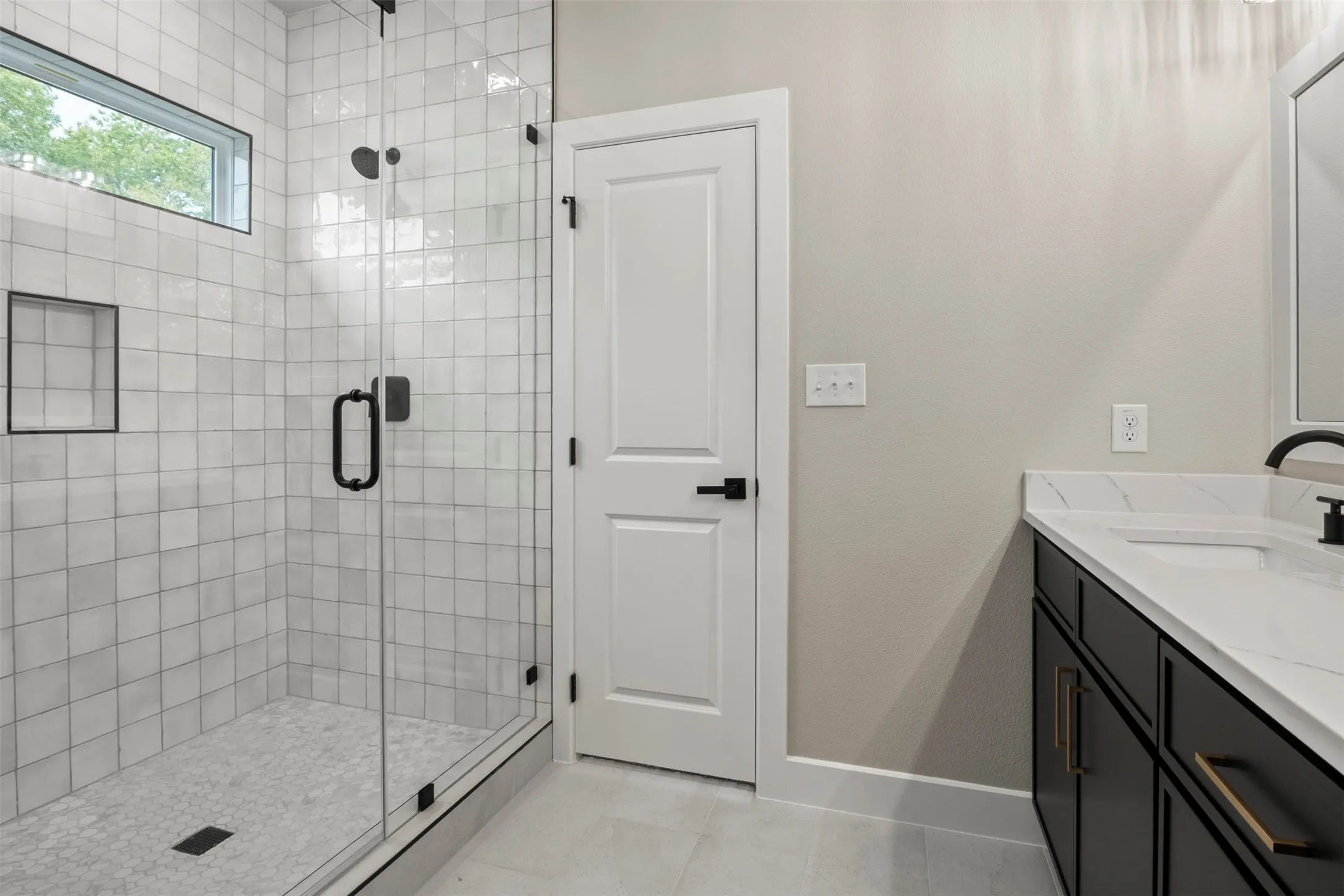 Glass-enclosed shower with subway tile surround, integrated shower niche, and small transom window