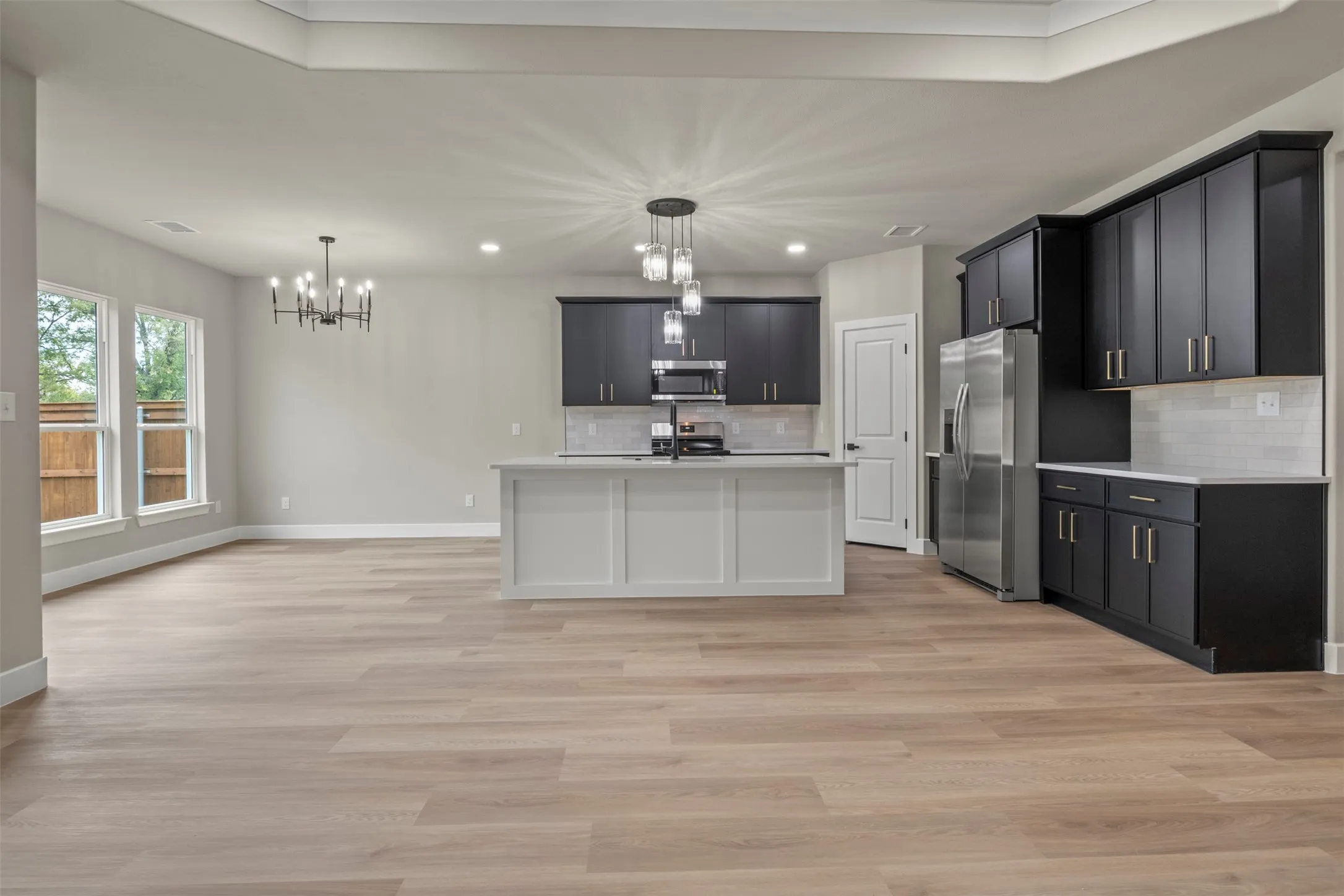Open-concept living area featuring wood-finish flooring, a modern chandelier, and recessed lighting