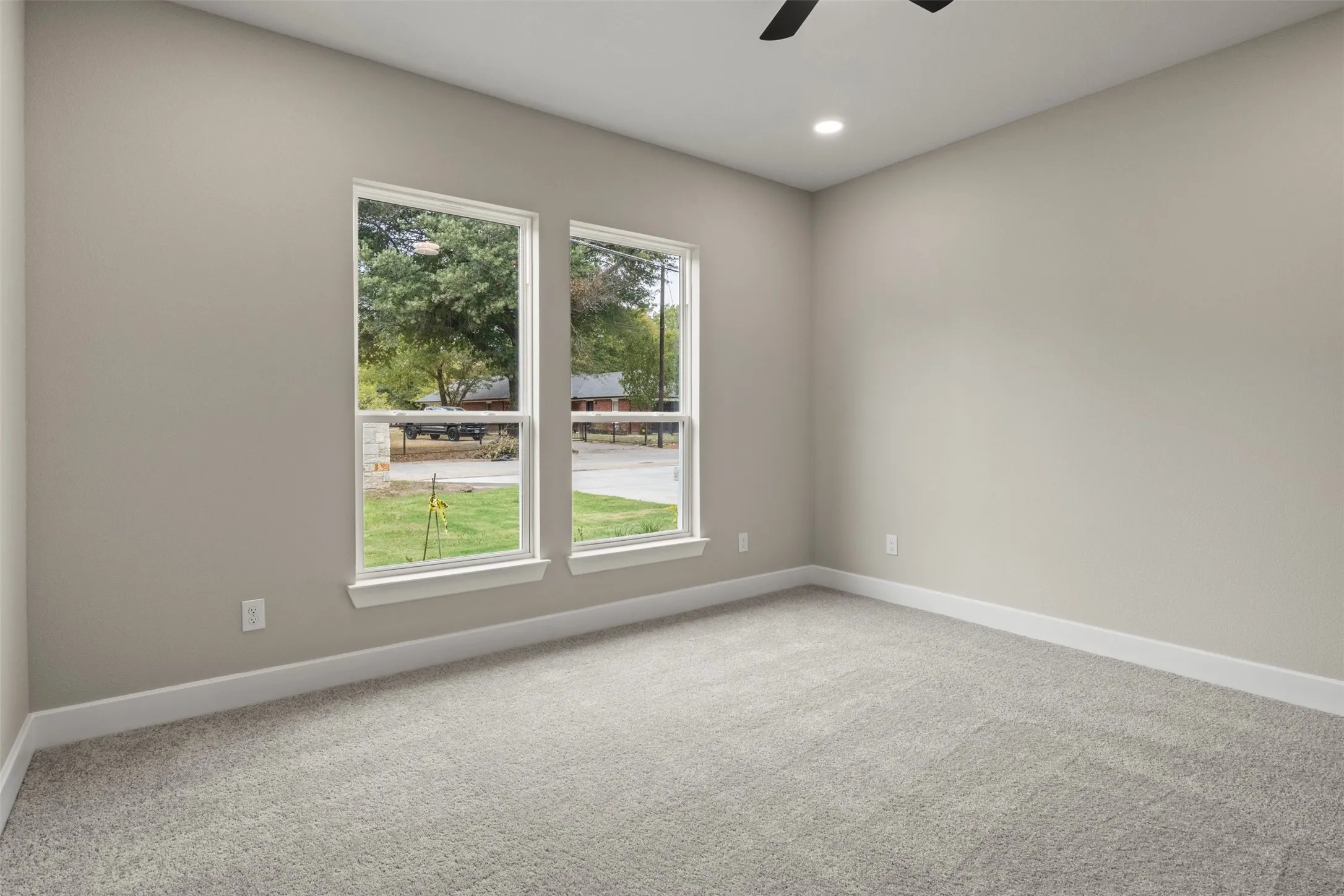 Carpeted room with neutral wall tones, two large windows, white trim, and a ceiling-mounted light fixture