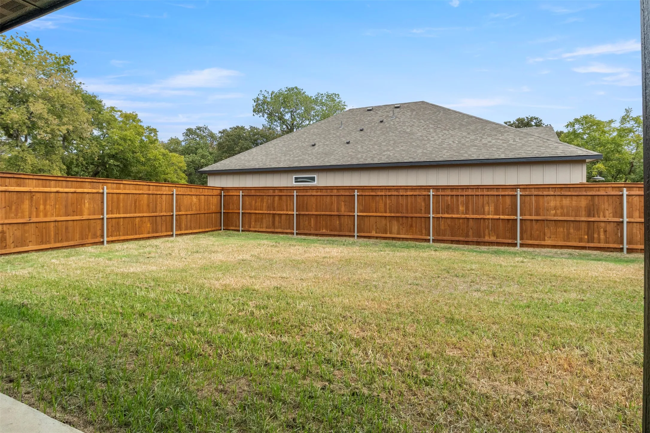Expansive backyard with a wood privacy fence and established trees