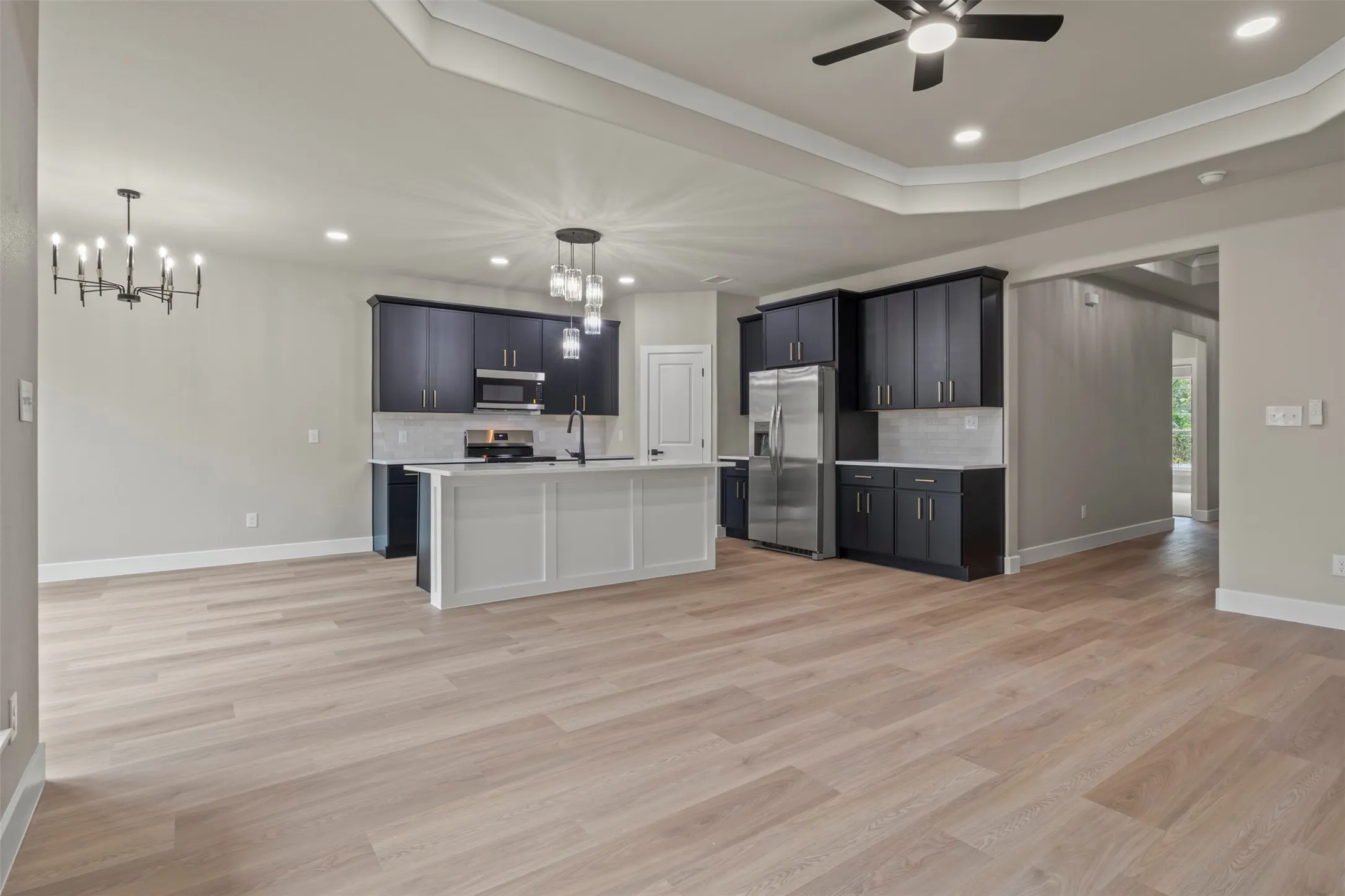 Kitchen featuring dark cabinetry, stainless steel appliances, a white island, and light wood-finish flooring