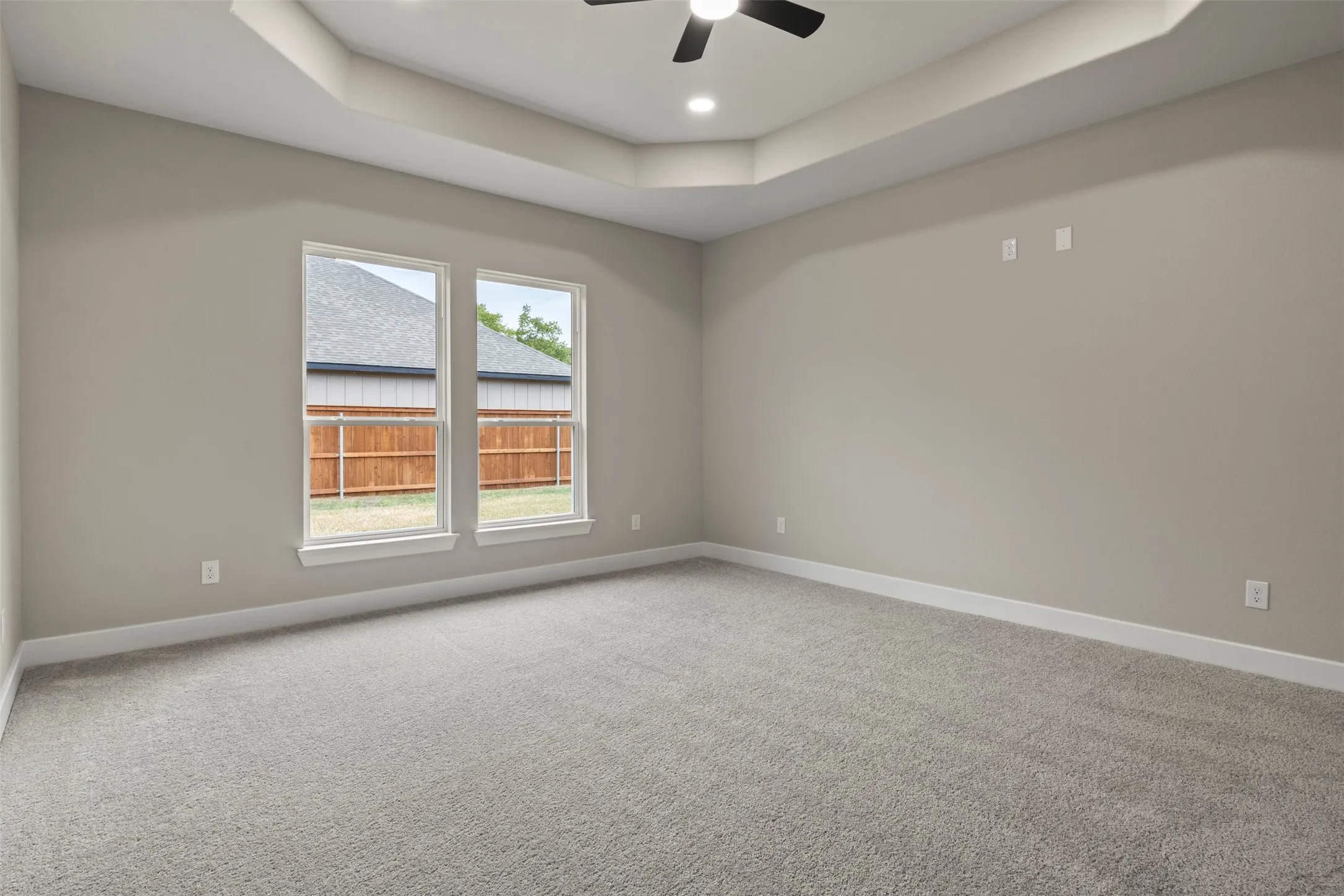 Tray ceiling with recessed lighting, ceiling fan, and two windows