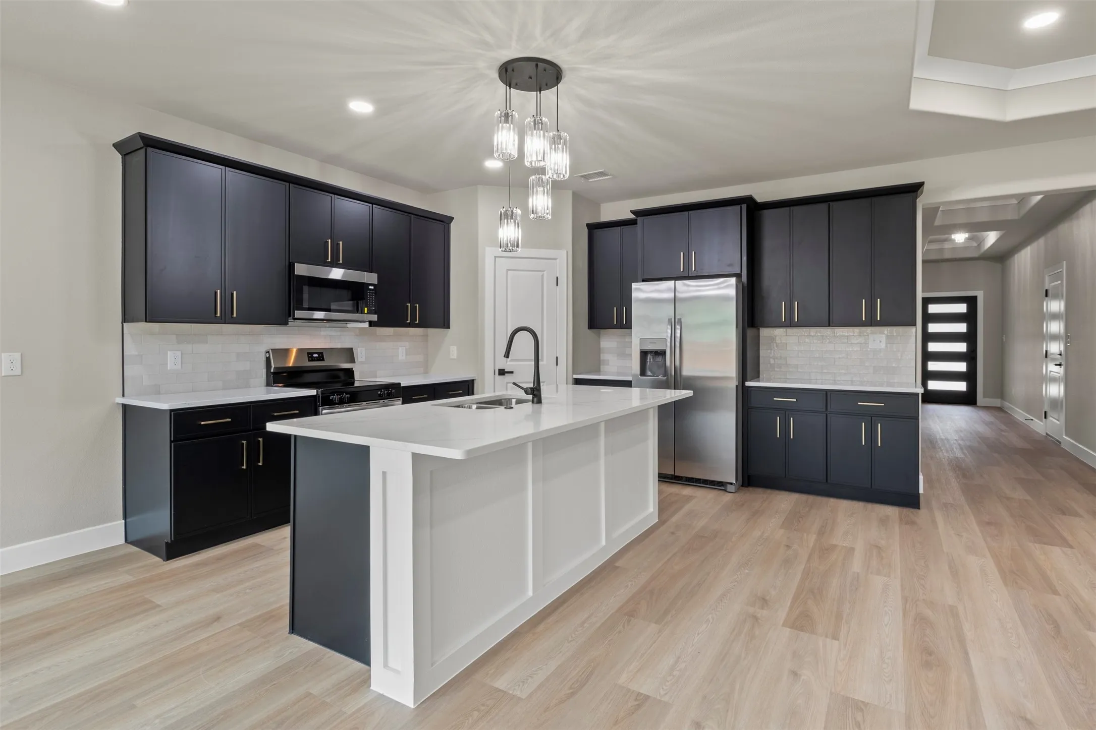Kitchen featuring dark cabinetry, white countertops, stainless steel appliances, and wood-finish flooring