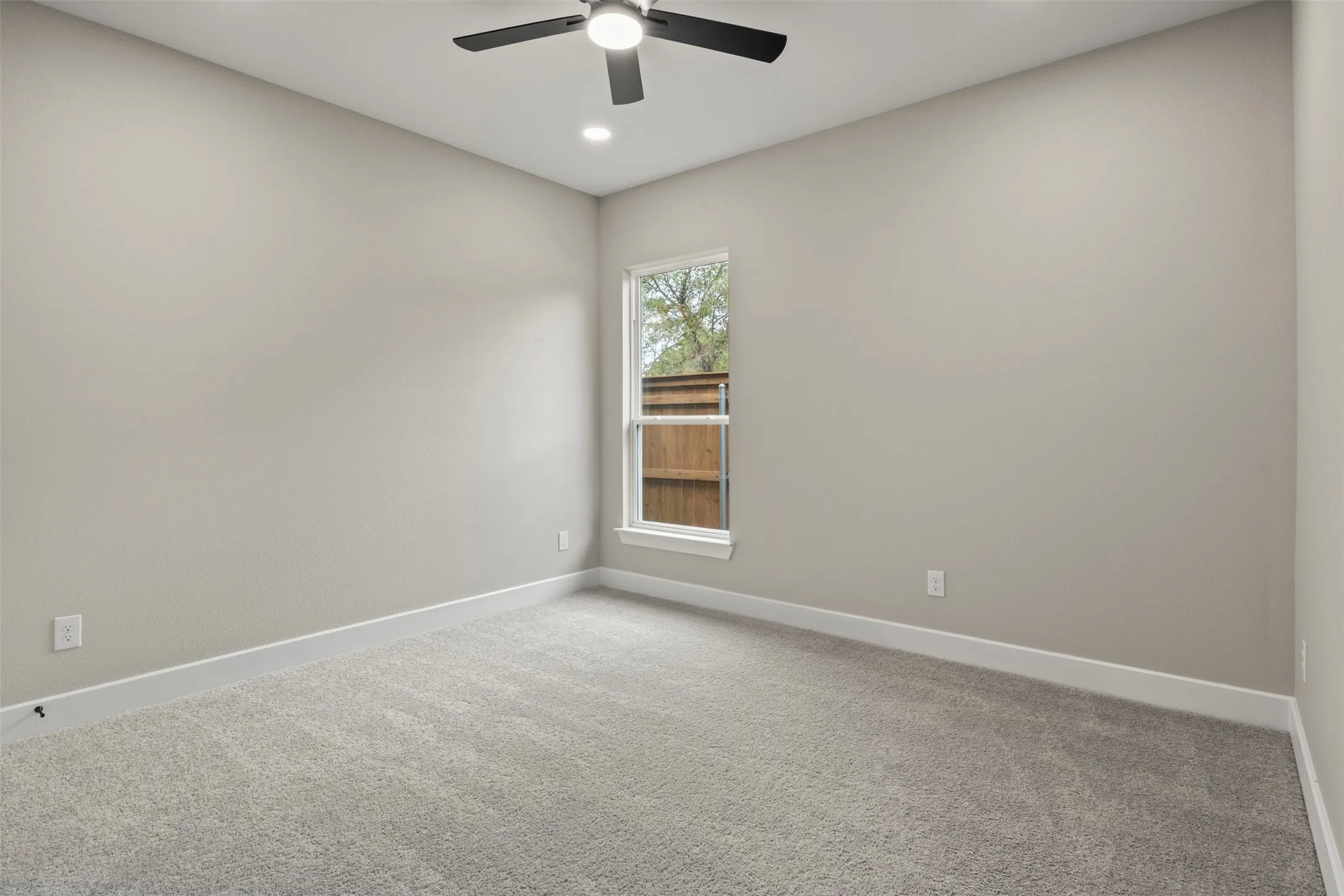 Neutral paint, recessed lighting, ceiling fan, carpeting, and window with exterior fencing