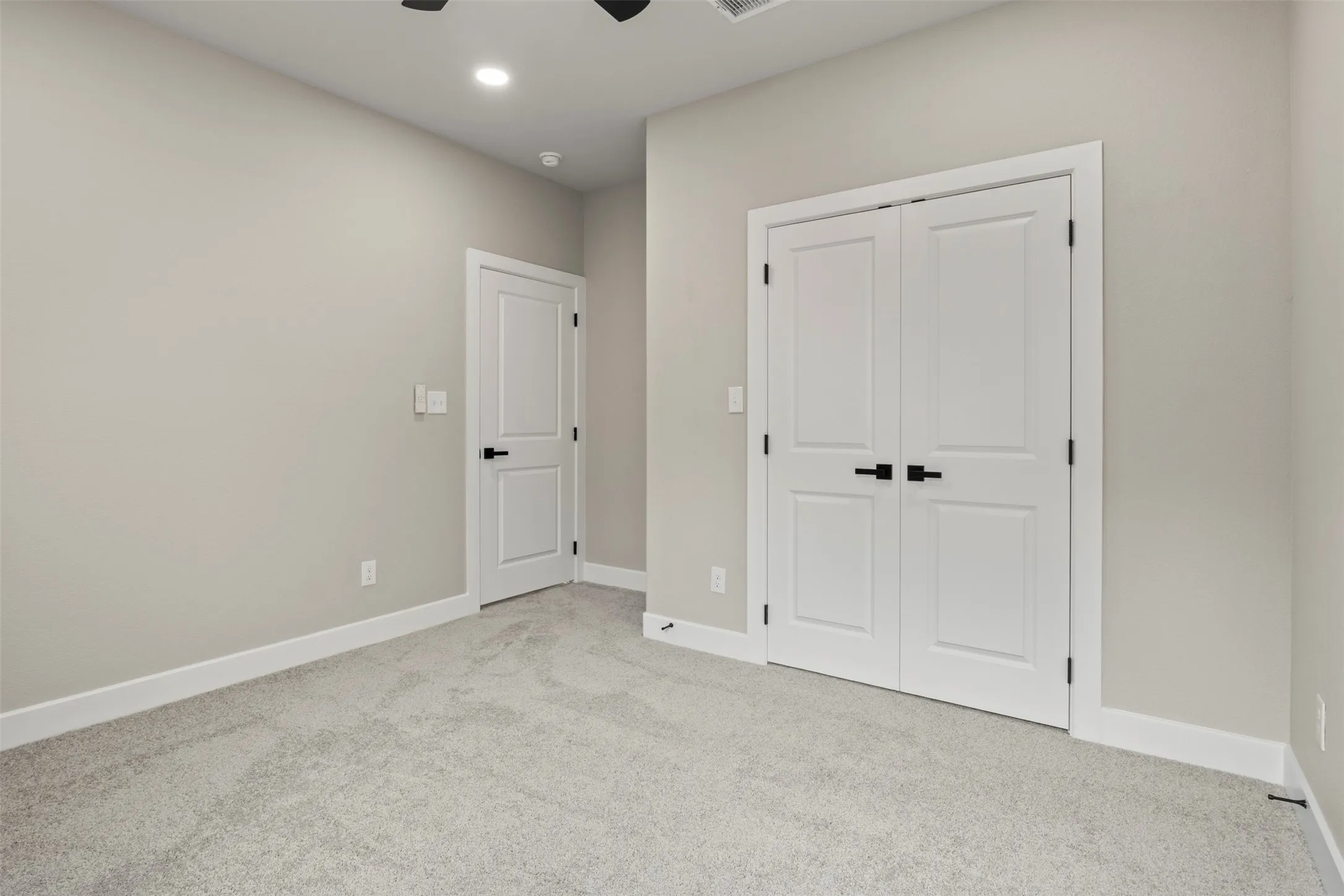 Wall-to-wall carpet flooring, neutral paint palette, white trim, recessed lighting, and black hardware