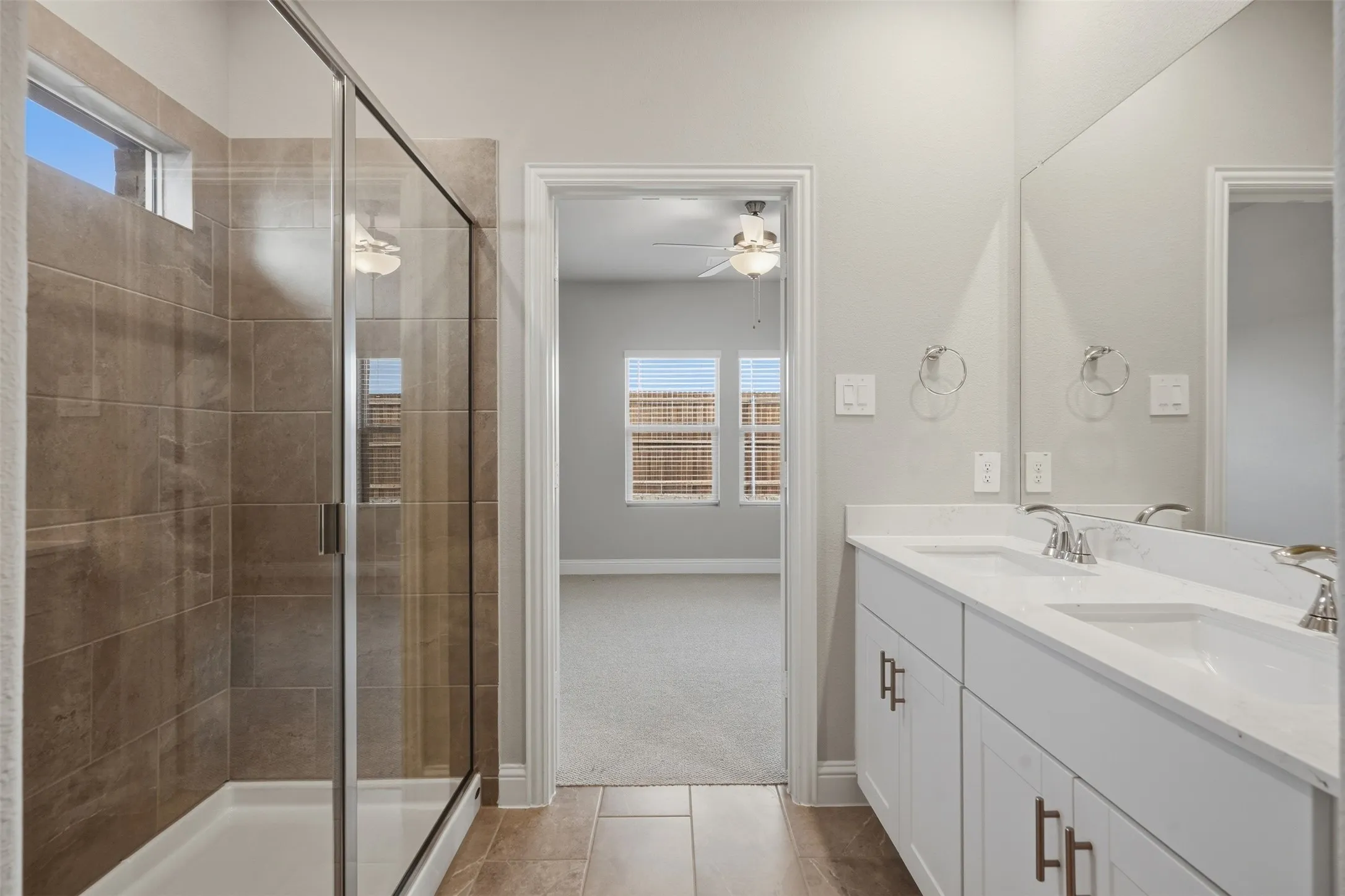 Dual vanity with white cabinetry, polished chrome fixtures, and a large mirror