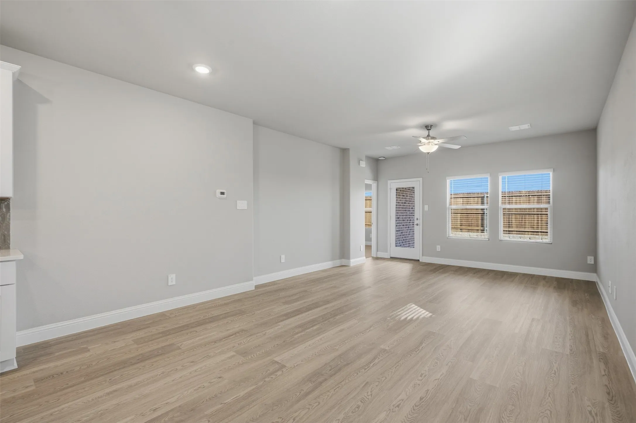Spacious room featuring wood-finish flooring, recessed lighting, and a ceiling fan