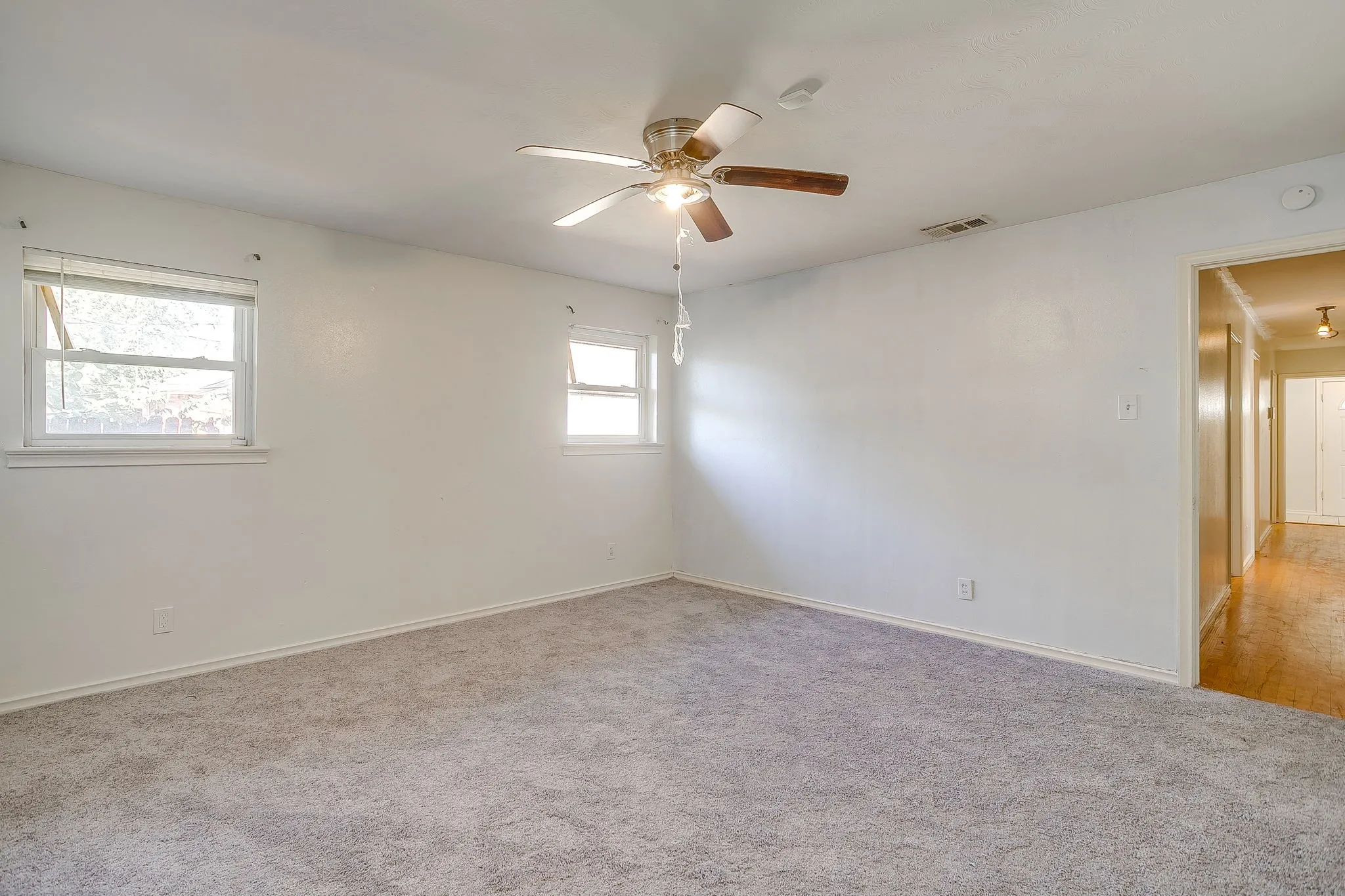 Neutral-toned carpeting, white painted walls, and a ceiling fan with light fixture