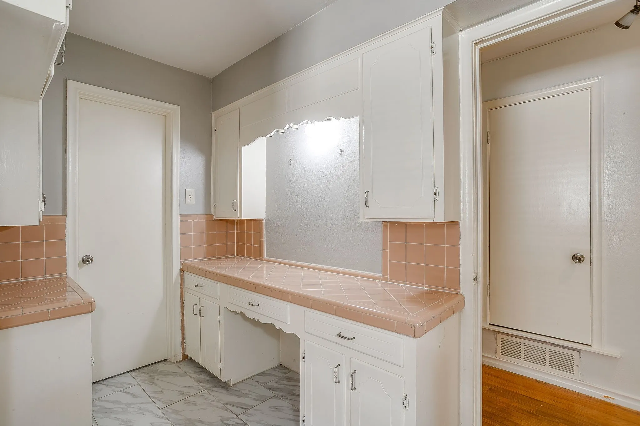 Large Guest Bathroom White cabinetry, built-in desk area, tiled countertops, tiled backsplash, and patterned floor tiling