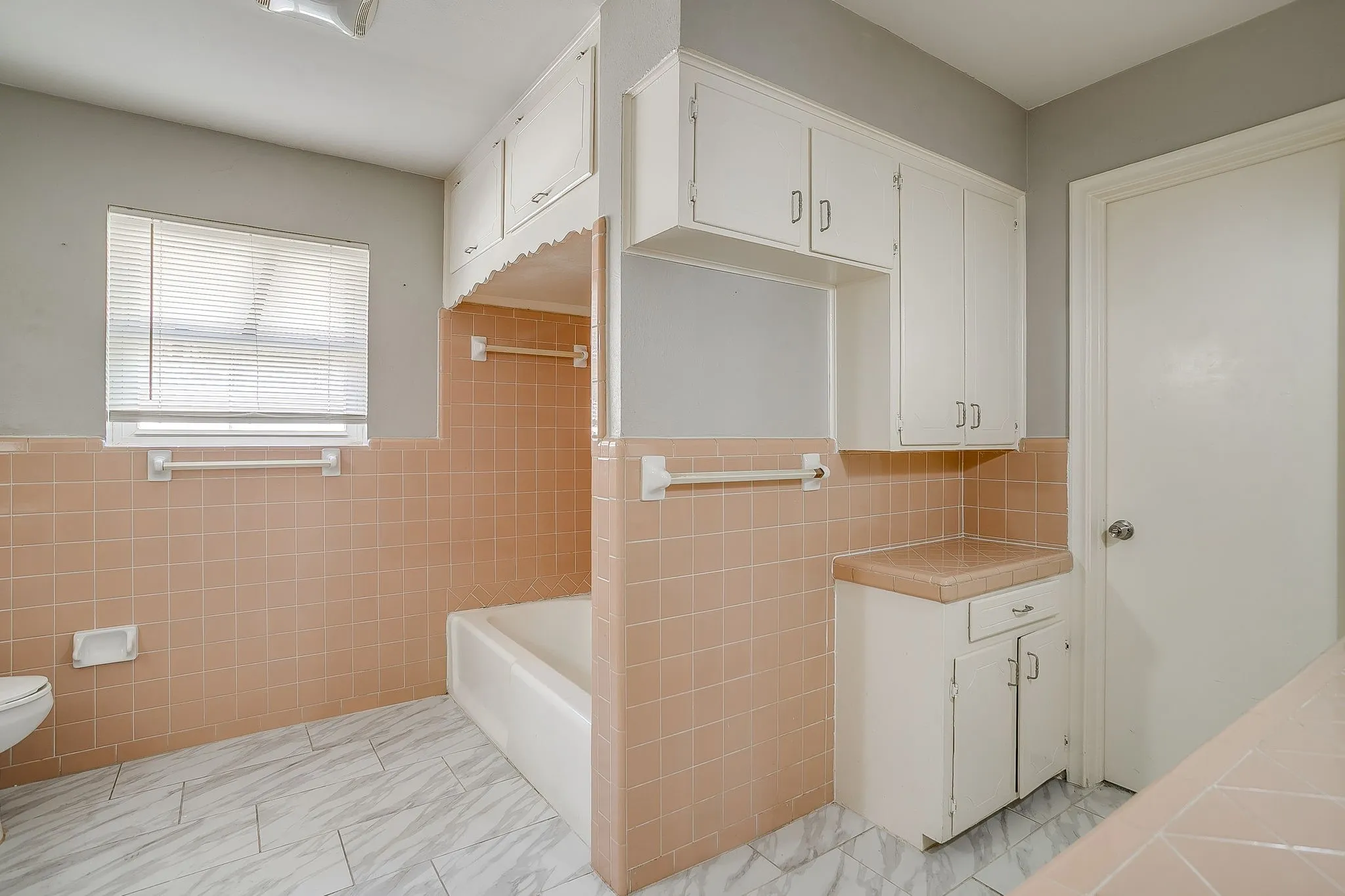 Large guest bathroom Built-in cabinetry, ceramic tile walls, and tiled flooring