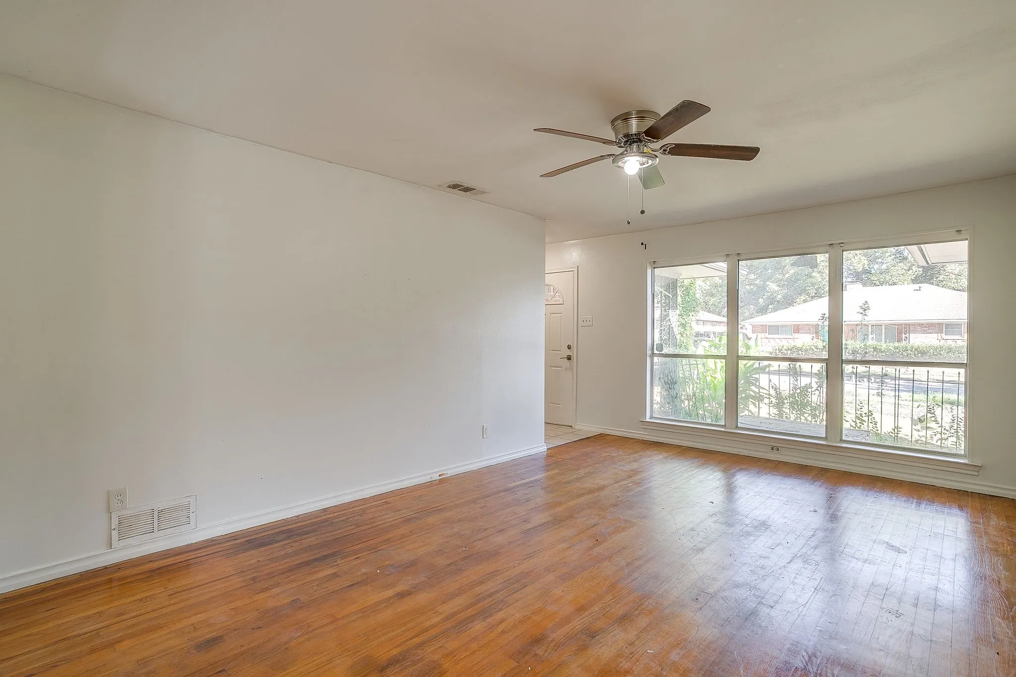 Hardwood flooring throughout, multiple large windows, and a ceiling fan