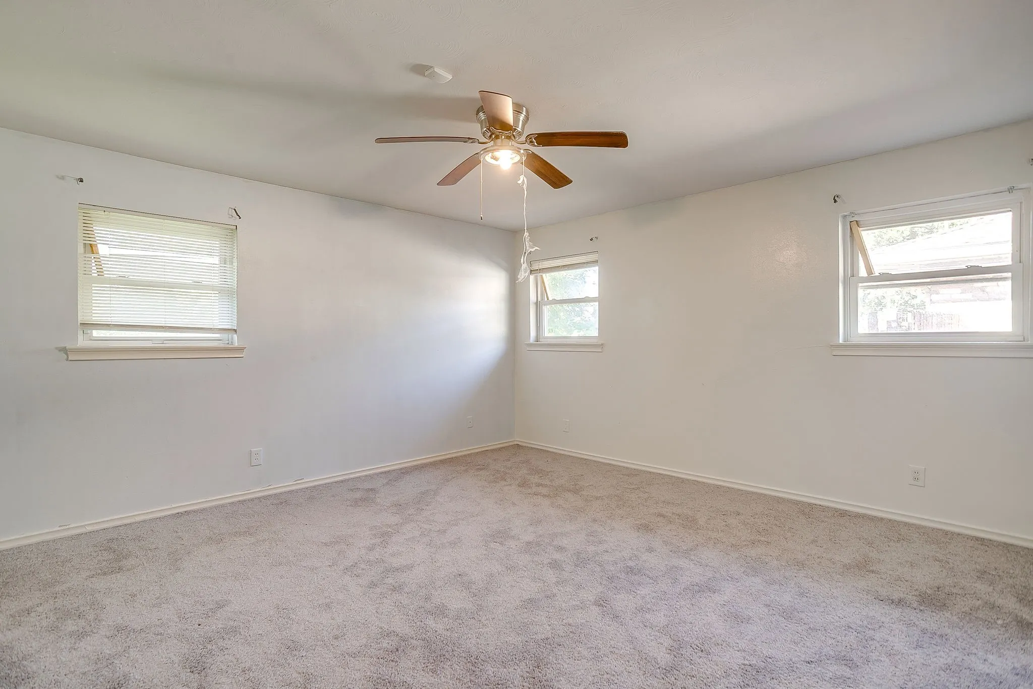 Neutral-toned carpeting, white walls, and multiple windows with blinds