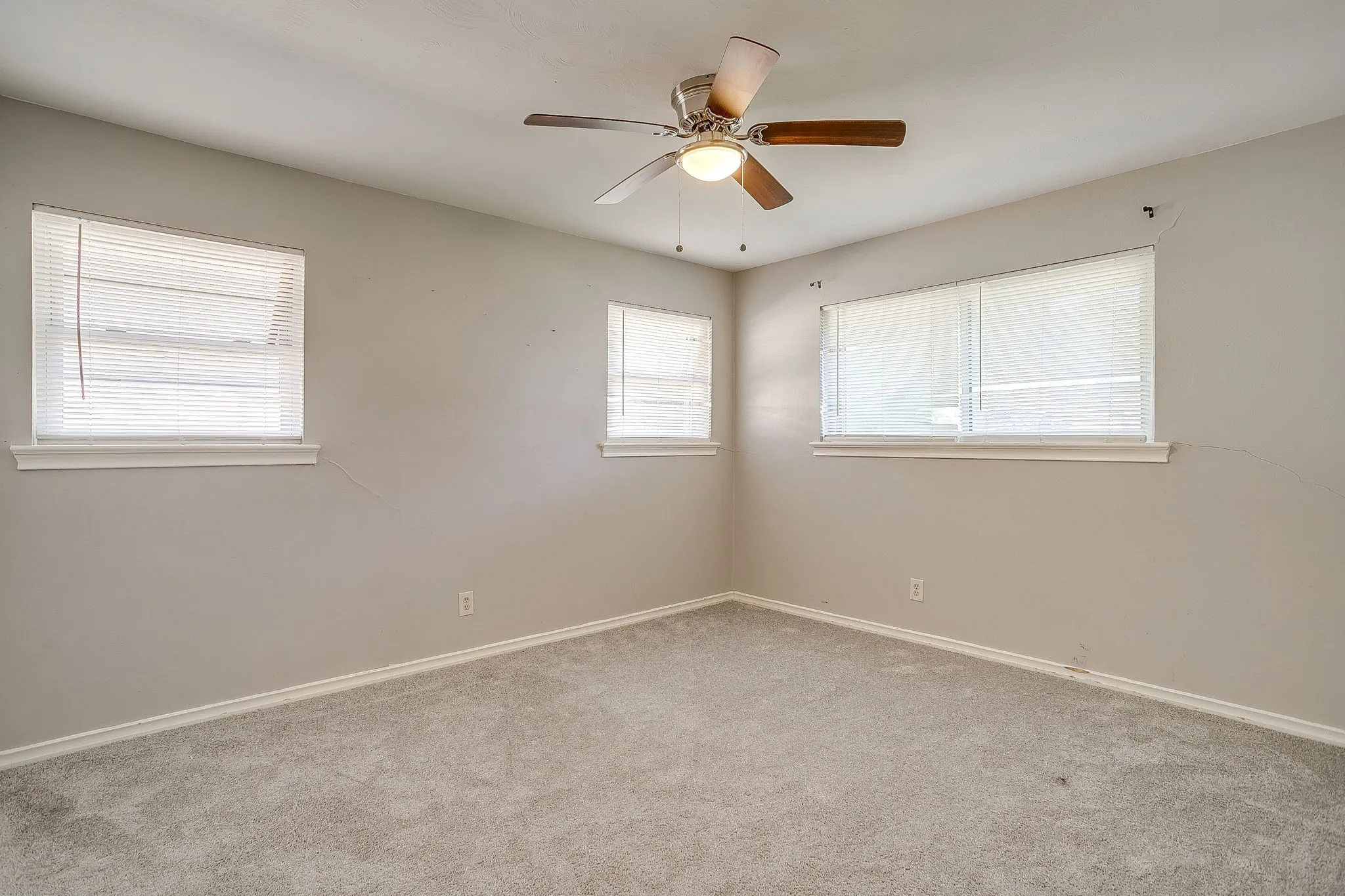 Carpeted flooring, multiple windows with blinds, and a ceiling fan with integrated lighting