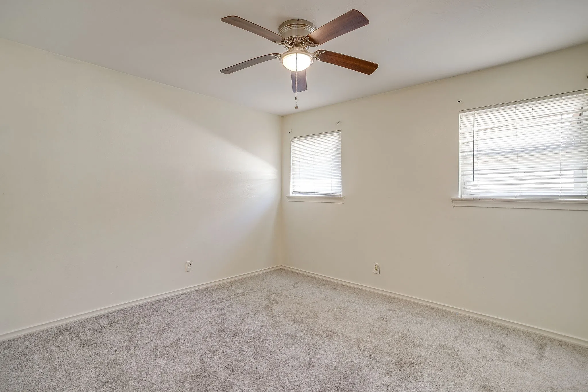 Guest bedroom #2 Neutral-toned walls, ceiling fan with integrated lighting, two windows with blinds, and light-colored carpeting