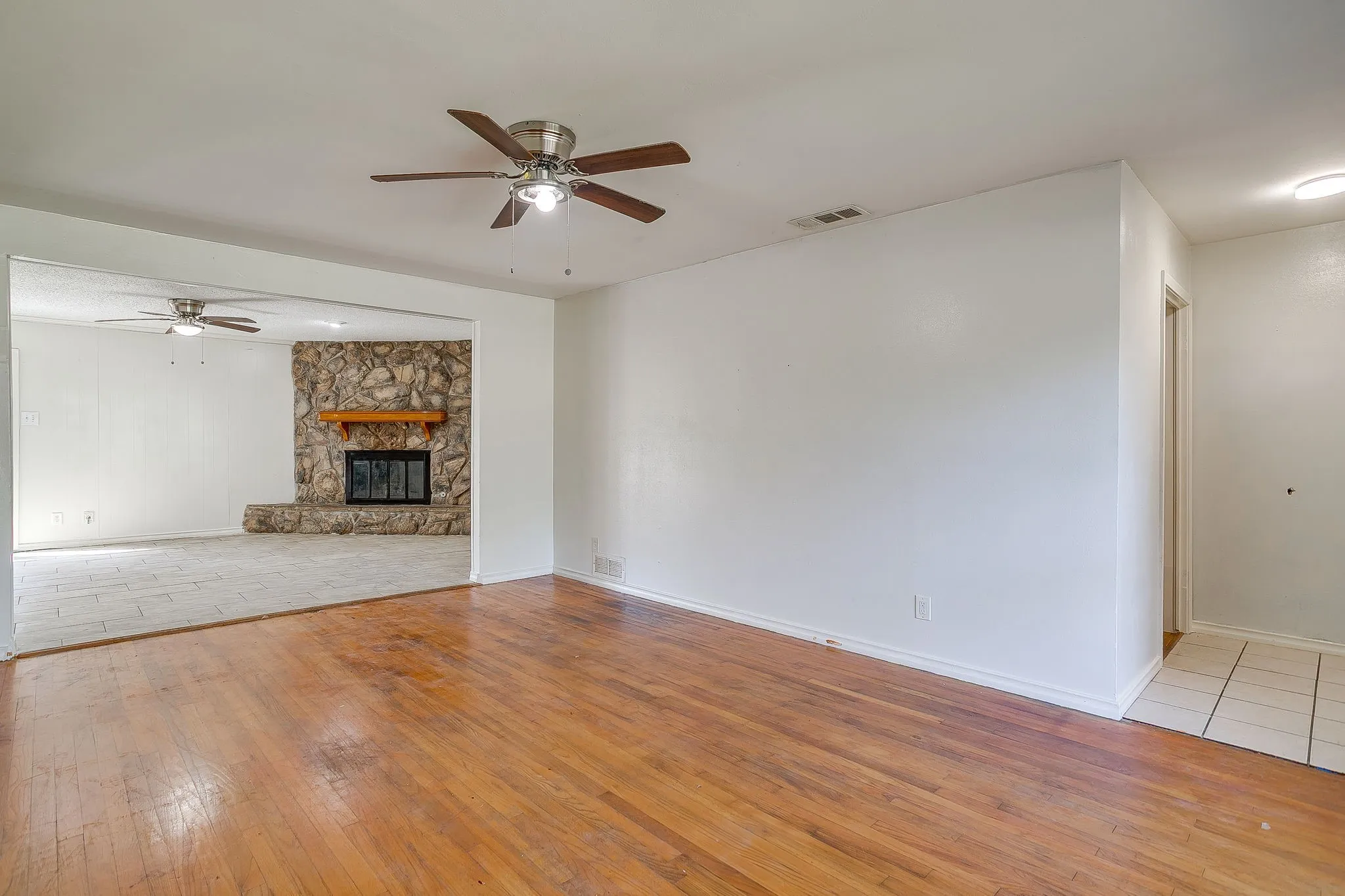 Wood-finish flooring, ceiling fan, and white walls in the main living area