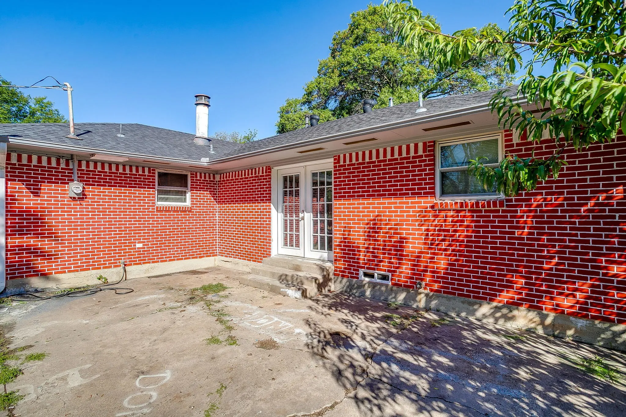 Red brick exterior featuring a patio area, double doors, and multiple windows