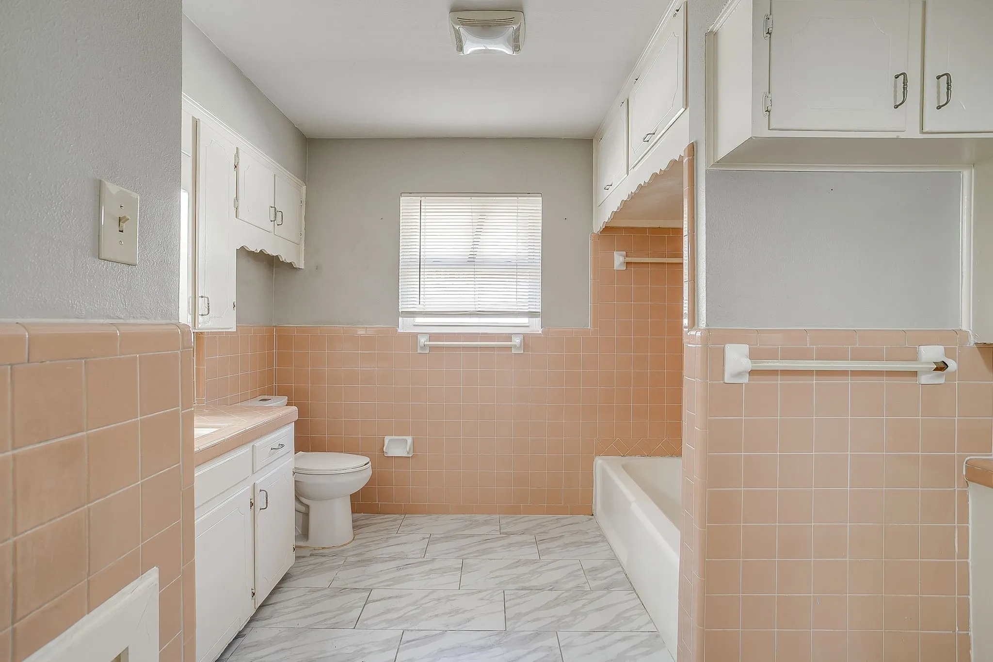 large guest Bathroom featuring pink wall tile, white cabinetry, and a built-in bathtub