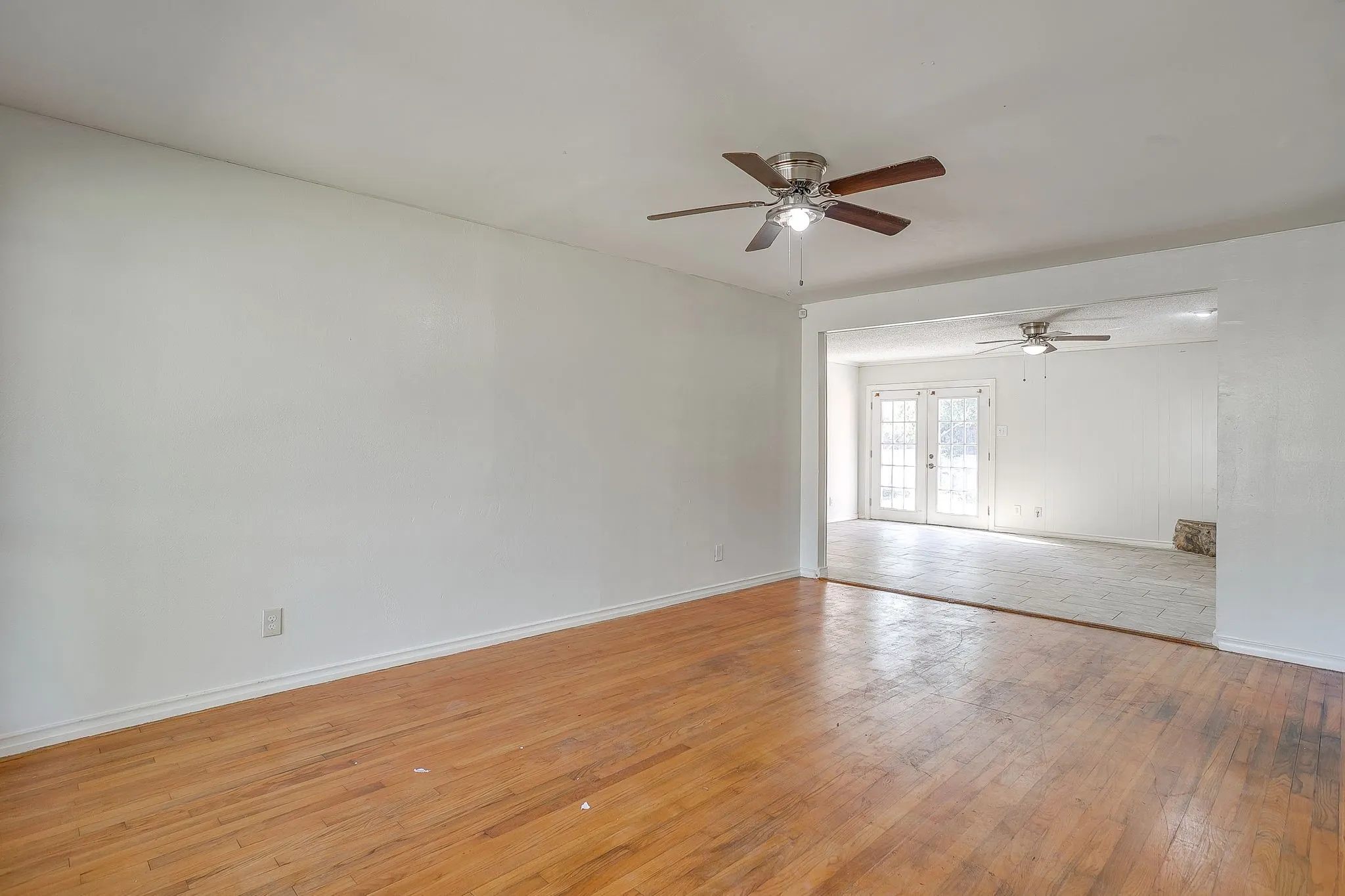 Hardwood flooring, white walls, and a ceiling fan in the main area