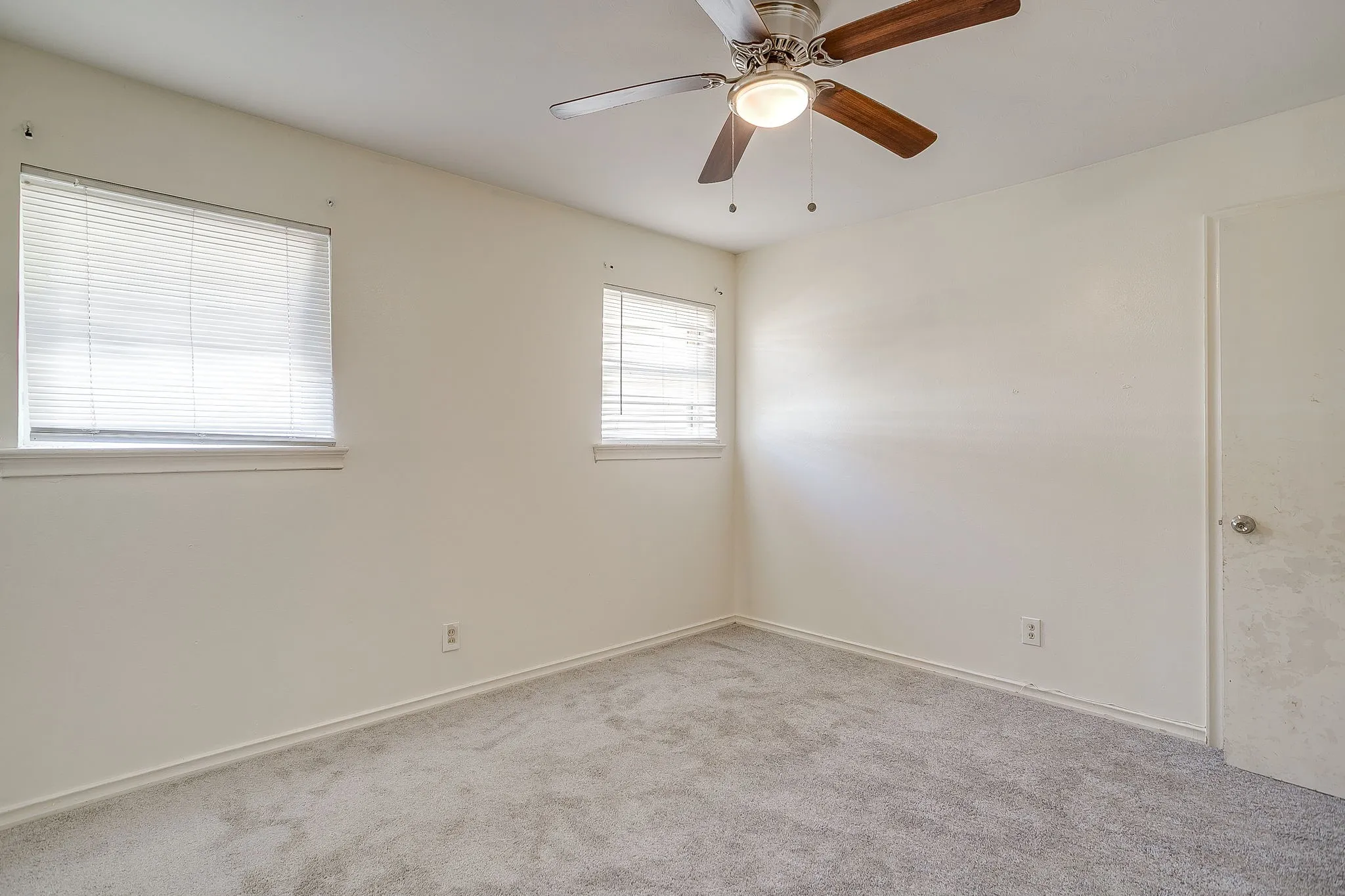 Carpeted room with two windows featuring horizontal blinds