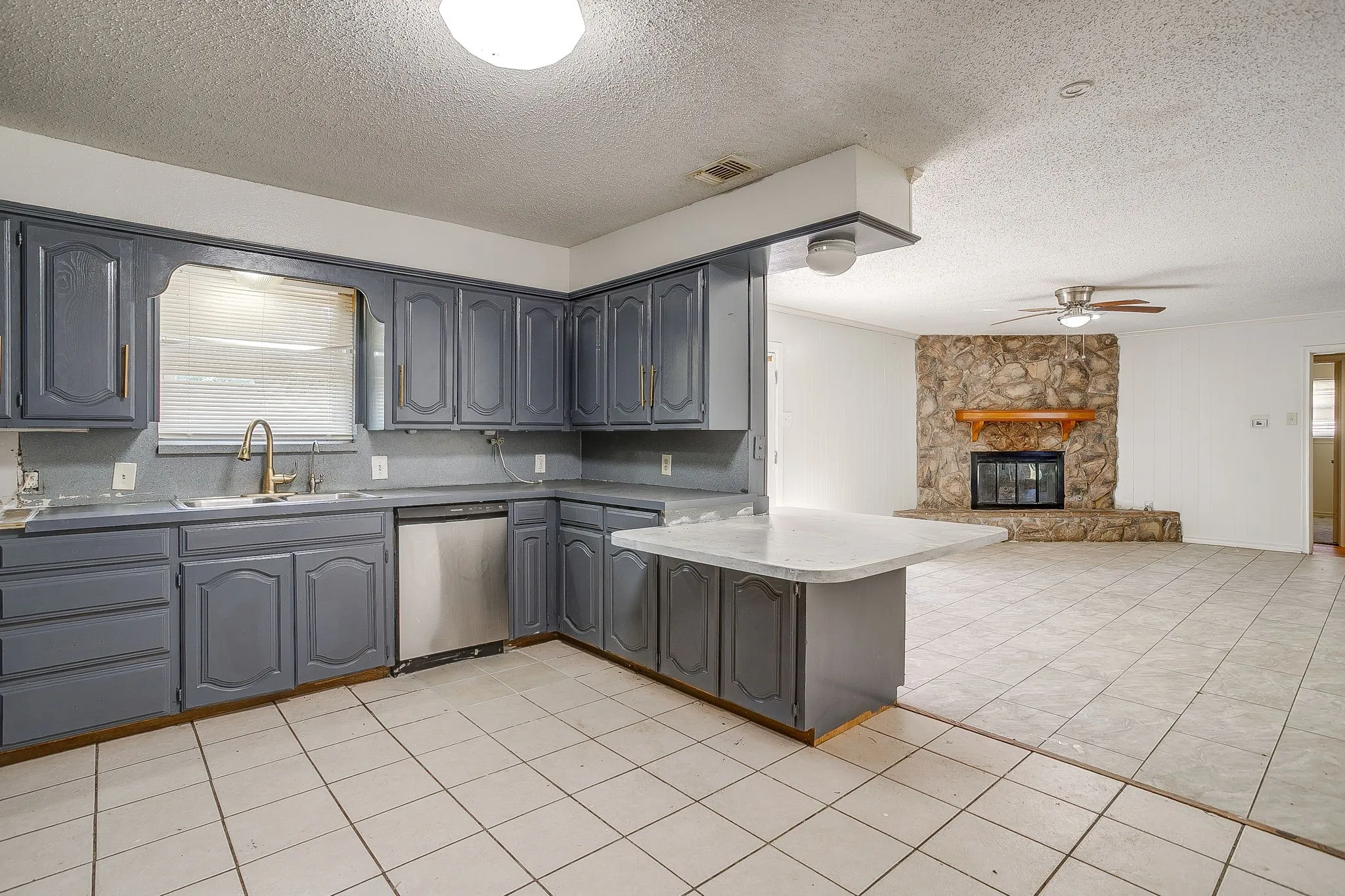 Kitchen featuring painted cabinetry, a stainless steel dishwasher, and a peninsula with a countertop