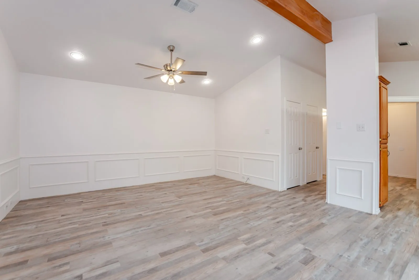 Vaulted ceiling, recessed lighting, wood-finish flooring, accent wall paneling, and ceiling fan