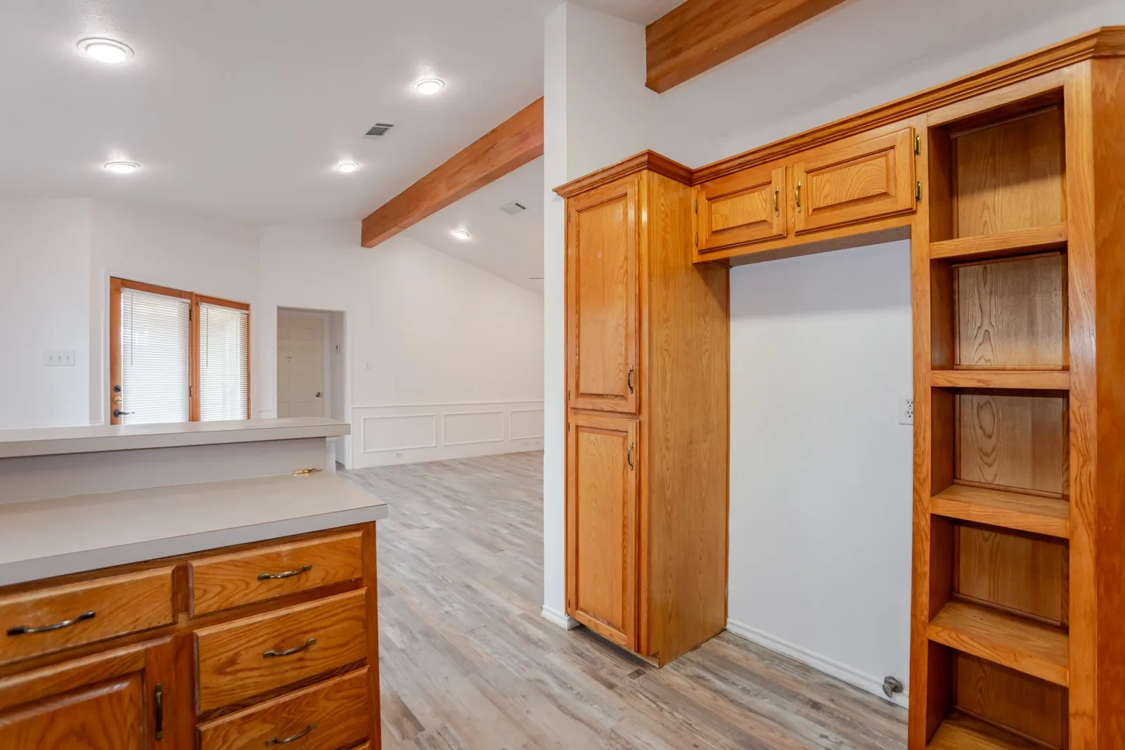 Wood-finish flooring throughout, featuring a kitchen peninsula with wood cabinetry and a light-toned countertop