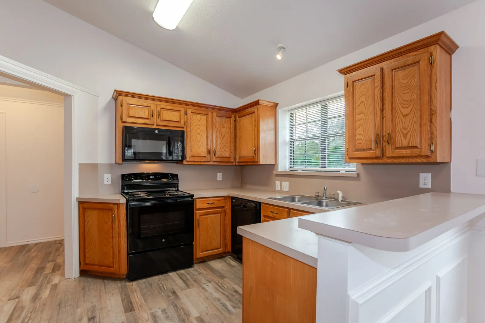 Kitchen featuring wood cabinetry, stone-finish countertops, and black appliances
