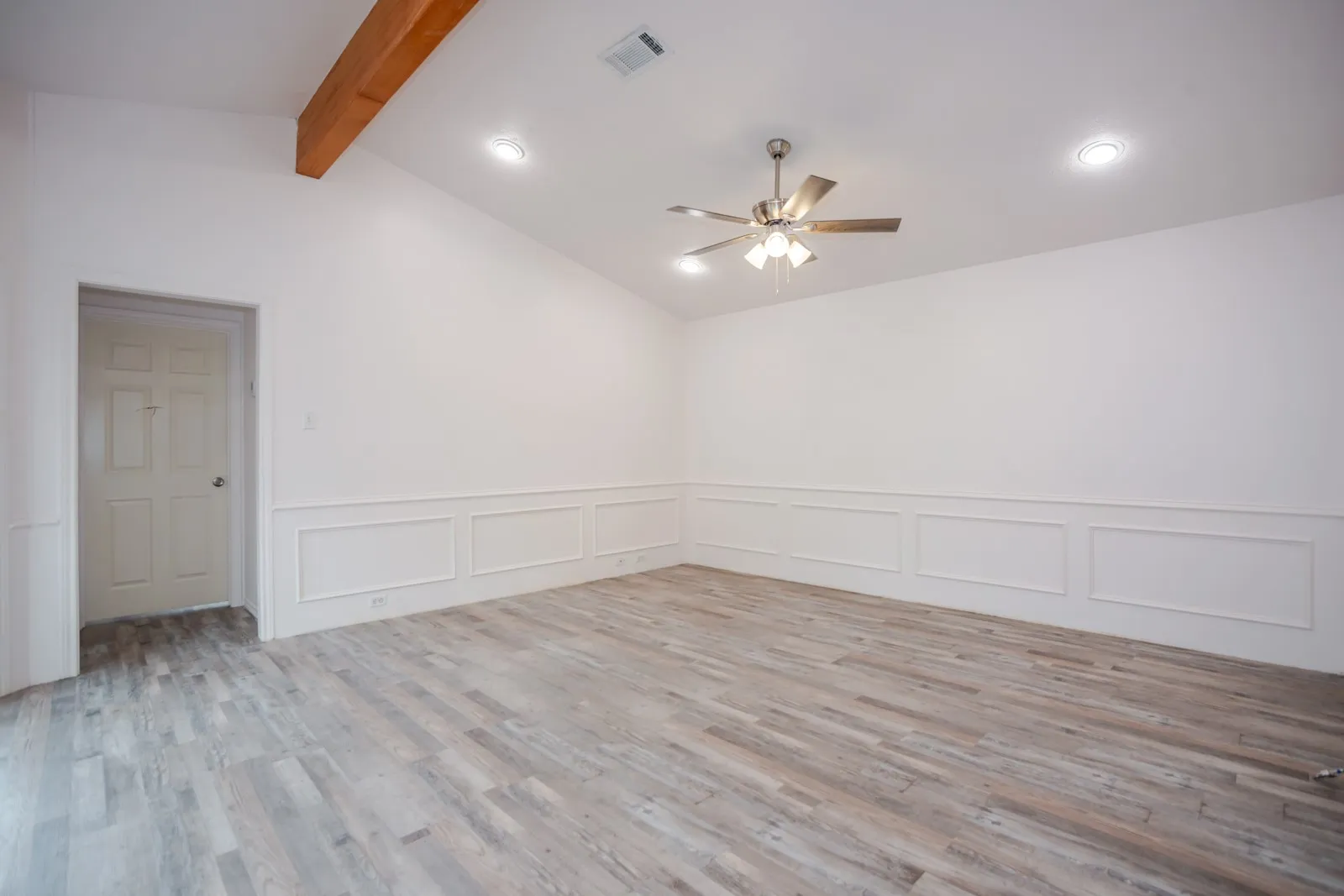Vaulted ceiling with exposed wood beam, recessed lighting, ceiling fan, wainscoting, and wood-finish flooring
