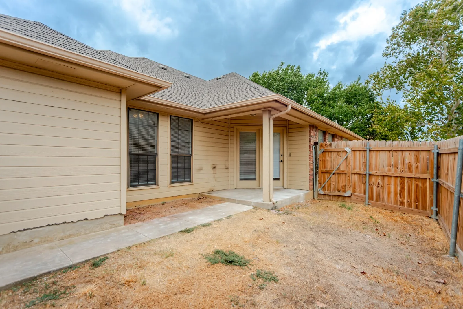 Covered patio with a concrete slab, wood fencing, and exterior siding