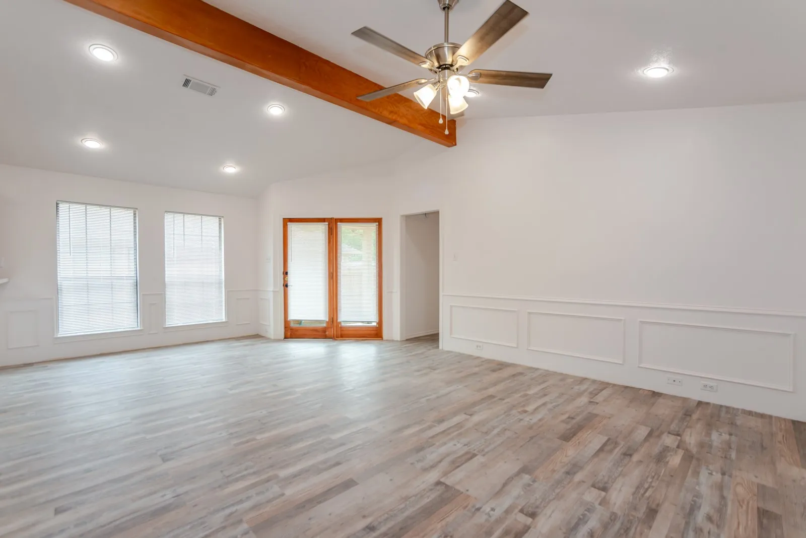 Vaulted ceiling with an exposed wood beam, wood-finish flooring, recessed lighting, and wall paneling
