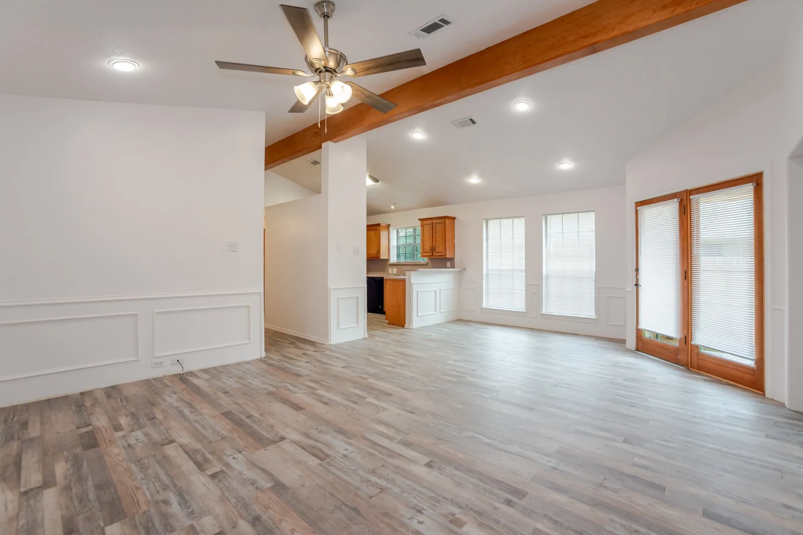 Spacious interior with wood-finish flooring, exposed ceiling beams, recessed lighting, and panel molding