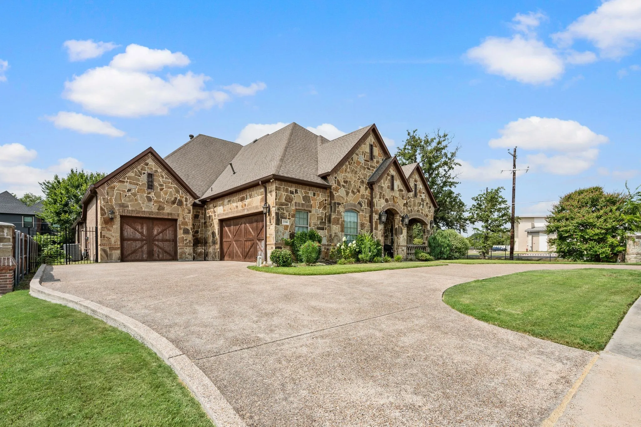 Stone exterior with multiple gables, arched entry, and two wood-finish garage doors