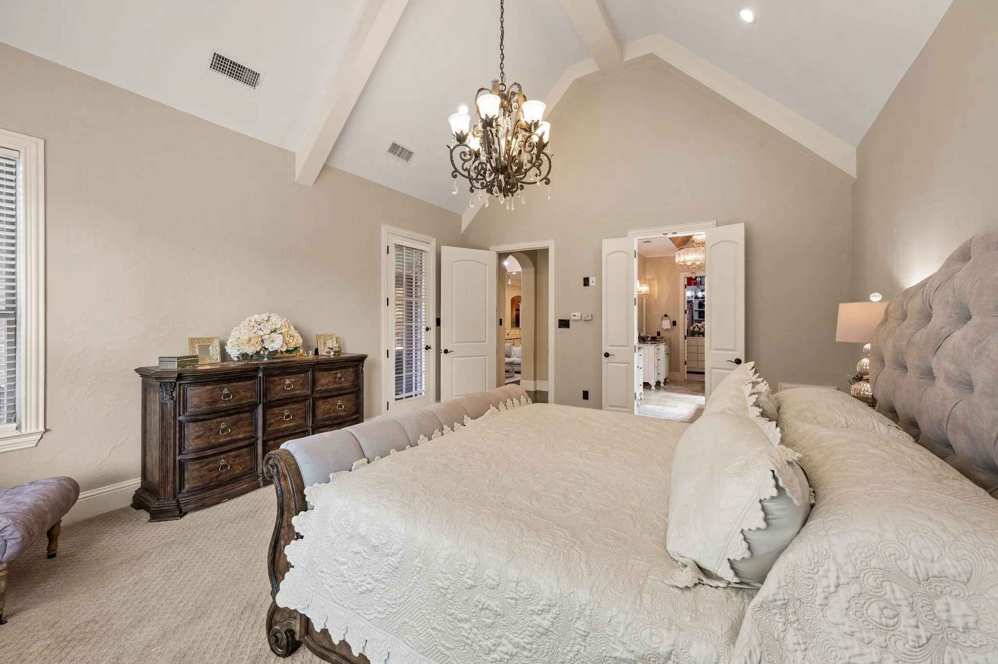 Vaulted ceiling with exposed beams, recessed lighting, and an ornate chandelier