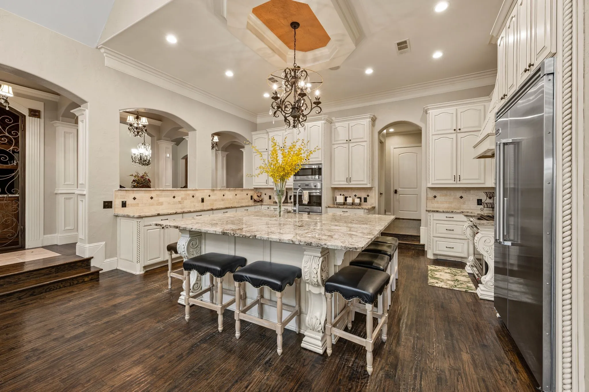 Gourmet kitchen with a large central island, light-toned cabinetry, integrated stainless steel appliances, and wood-finish flooring