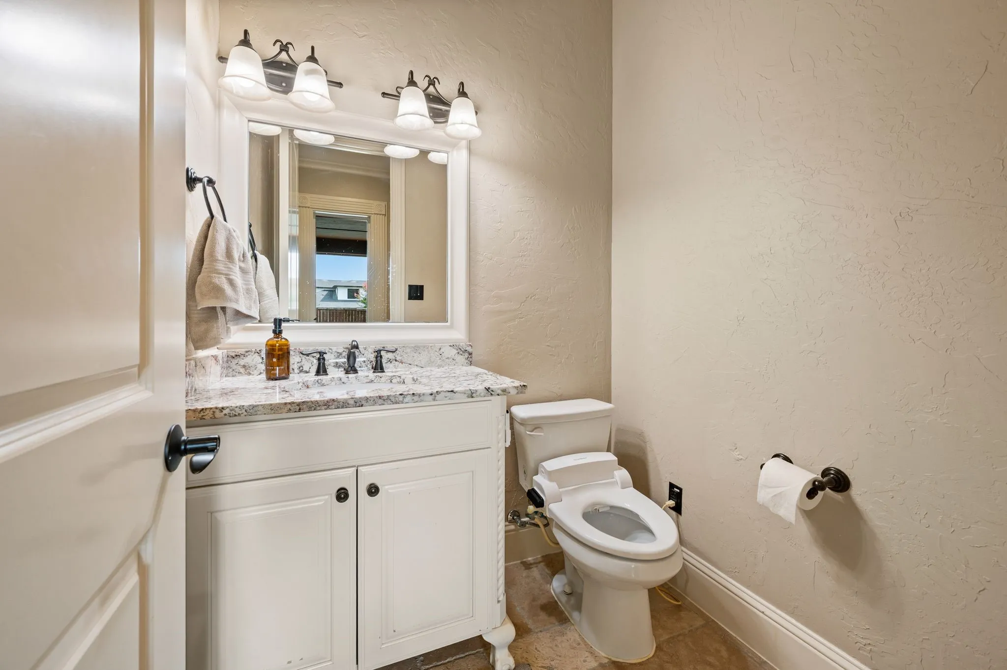 Vanity with a light-colored countertop, white cabinetry, and a framed mirror with an overhead light fixture
