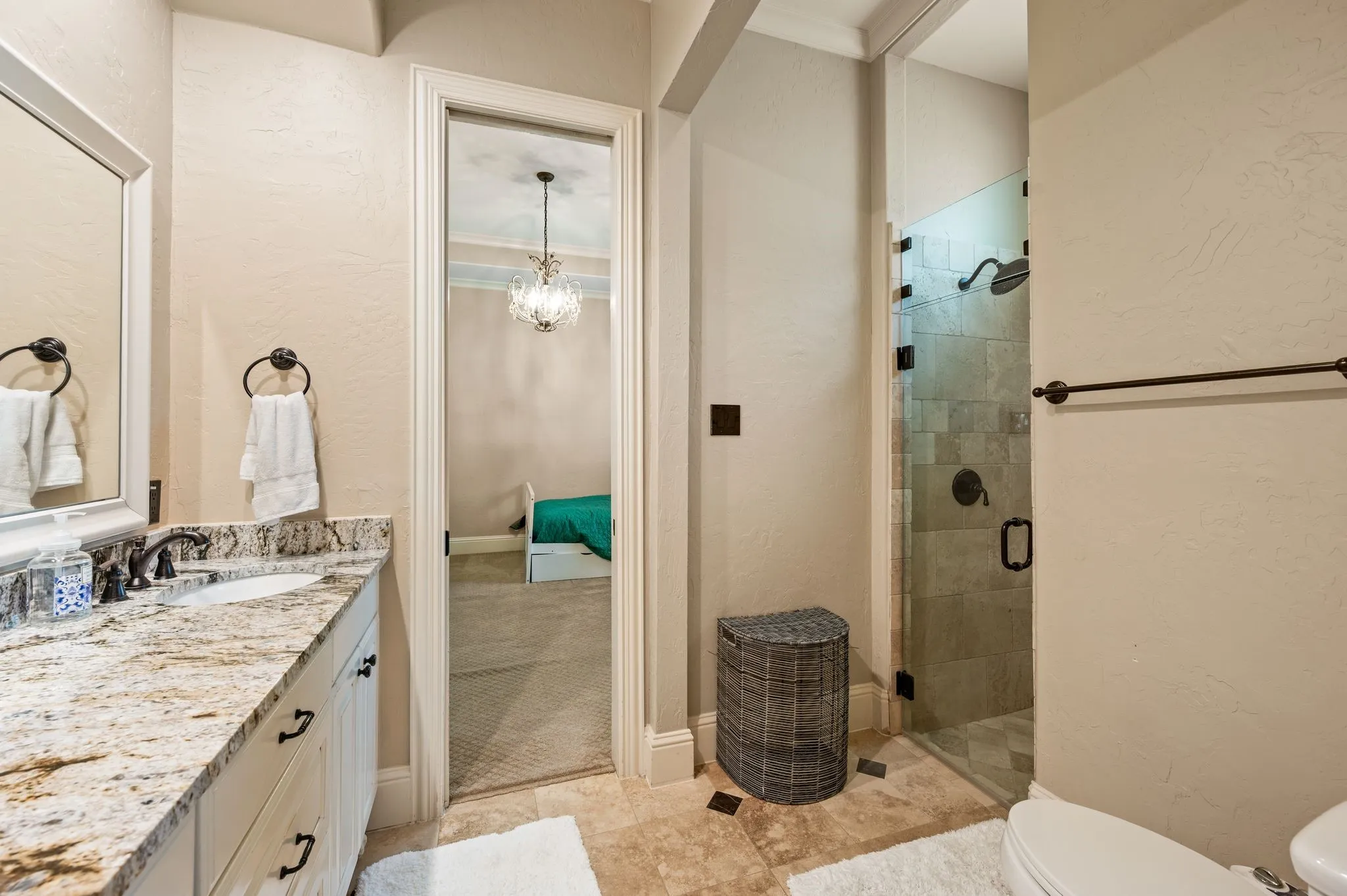 Vanity with a polished stone countertop and integrated sink, a glass-enclosed shower with tile surround, and a toilet