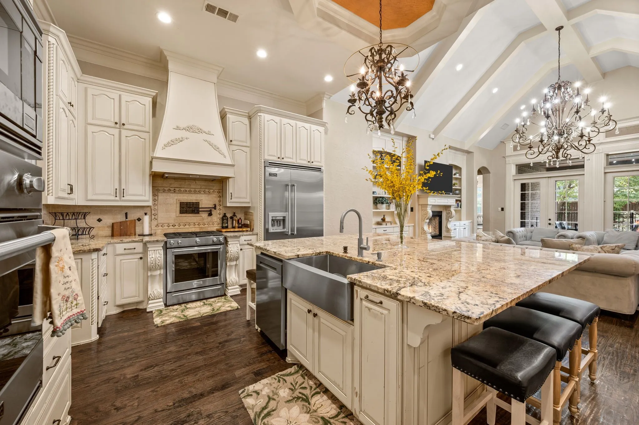 Gourmet kitchen with a large central island, granite countertops, stainless steel appliances, and wood-finish flooring