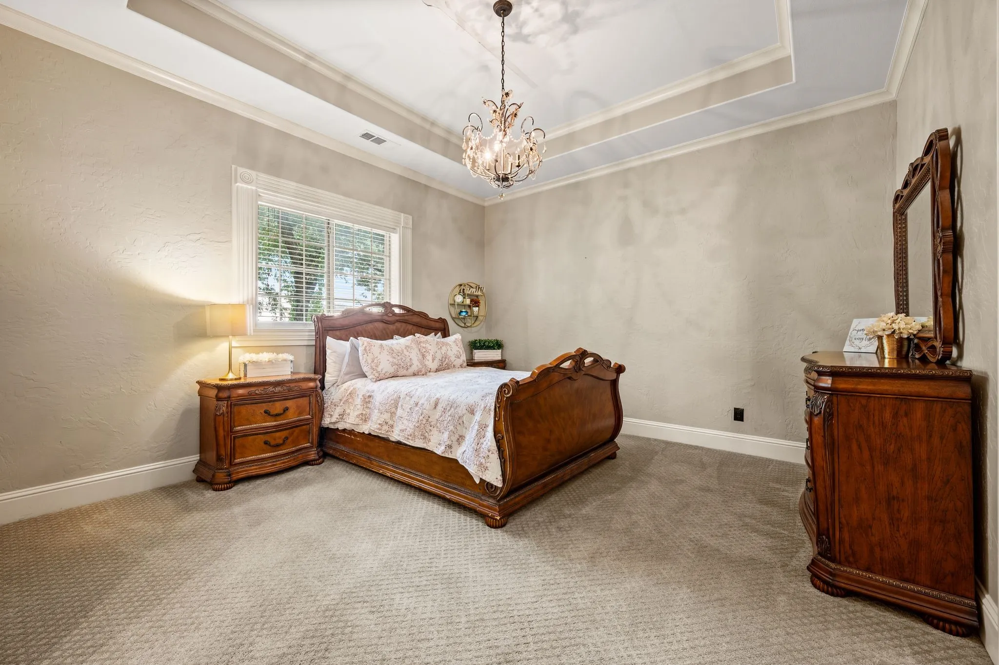 Tray ceiling with a chandelier, carpet flooring, window with blinds, and white trim