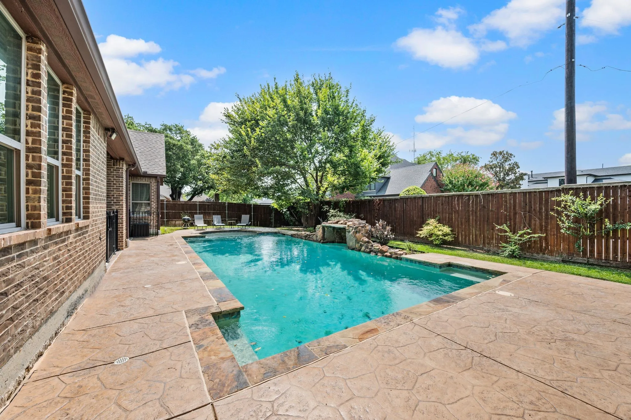 Rectangular swimming pool with integrated spa and rock waterfall feature