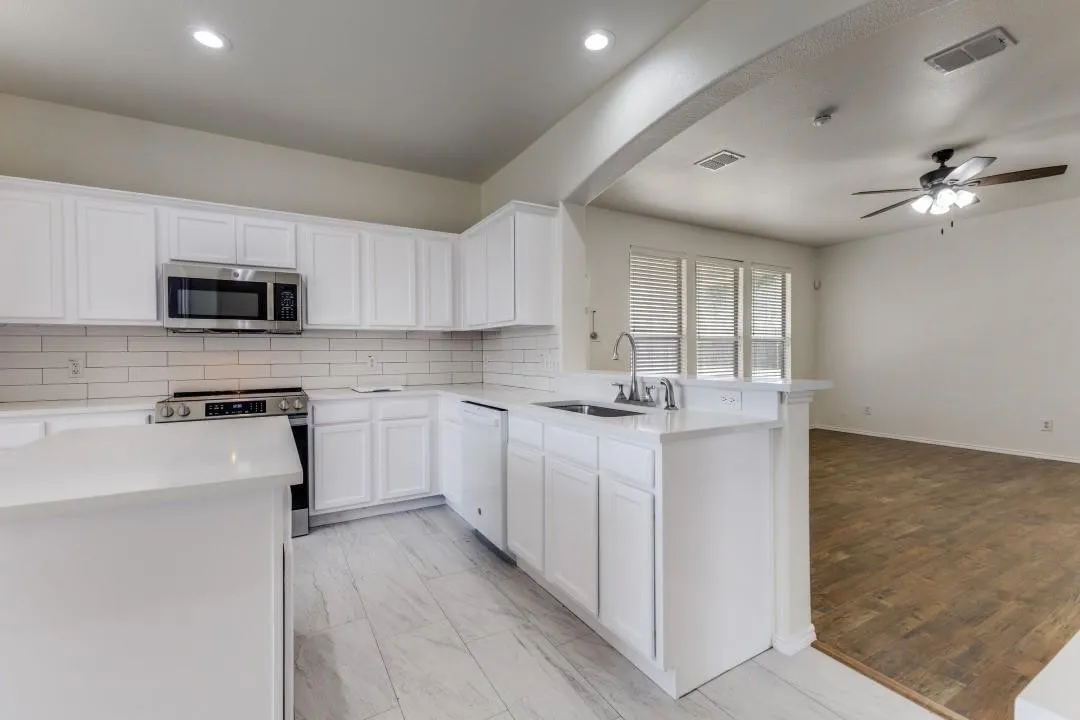 Modern kitchen with white cabinetry, stainless steel appliances, white subway tile backsplash, and light-toned flooring