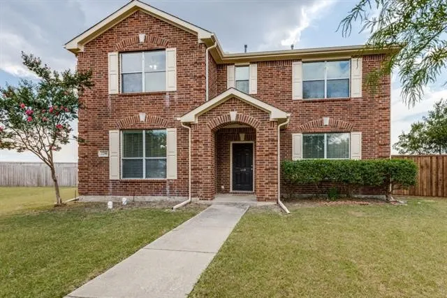 Brick exterior construction, arched entryway, white window shutters, mature landscaping, and a concrete walkway