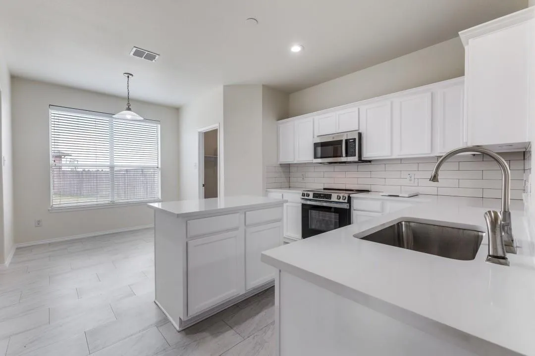 Modern kitchen featuring white cabinetry, subway tile backsplash, stainless steel appliances, a center island, and light-toned tile flooring