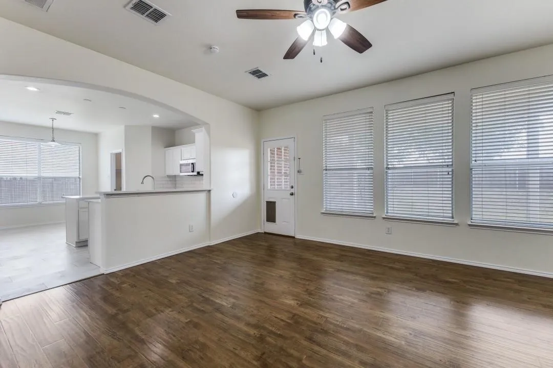 Wood-finish flooring throughout the main area, featuring an arched doorway and a ceiling fan with integrated lighting