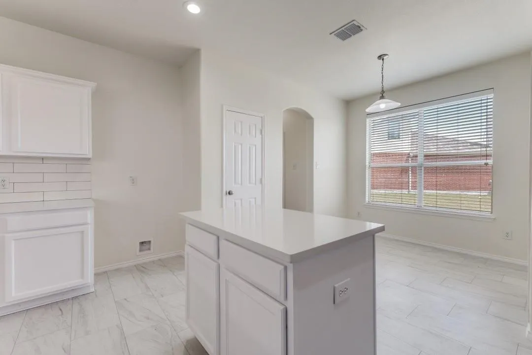 White shaker cabinetry, subway tile backsplash, white countertop, central island with integrated outlets, and tile flooring